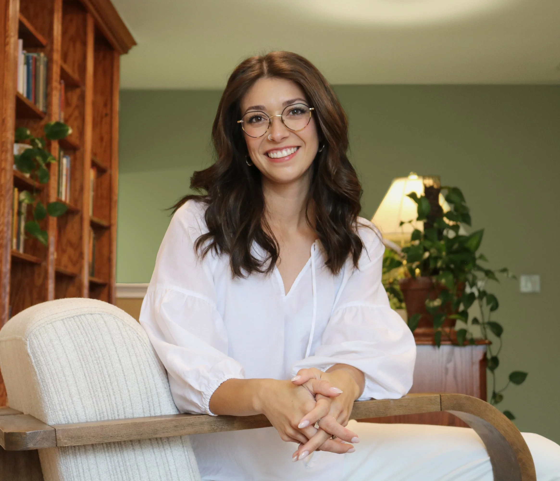 Gabby Lux, LPC, seated in a therapy office, smiling at the camera.
