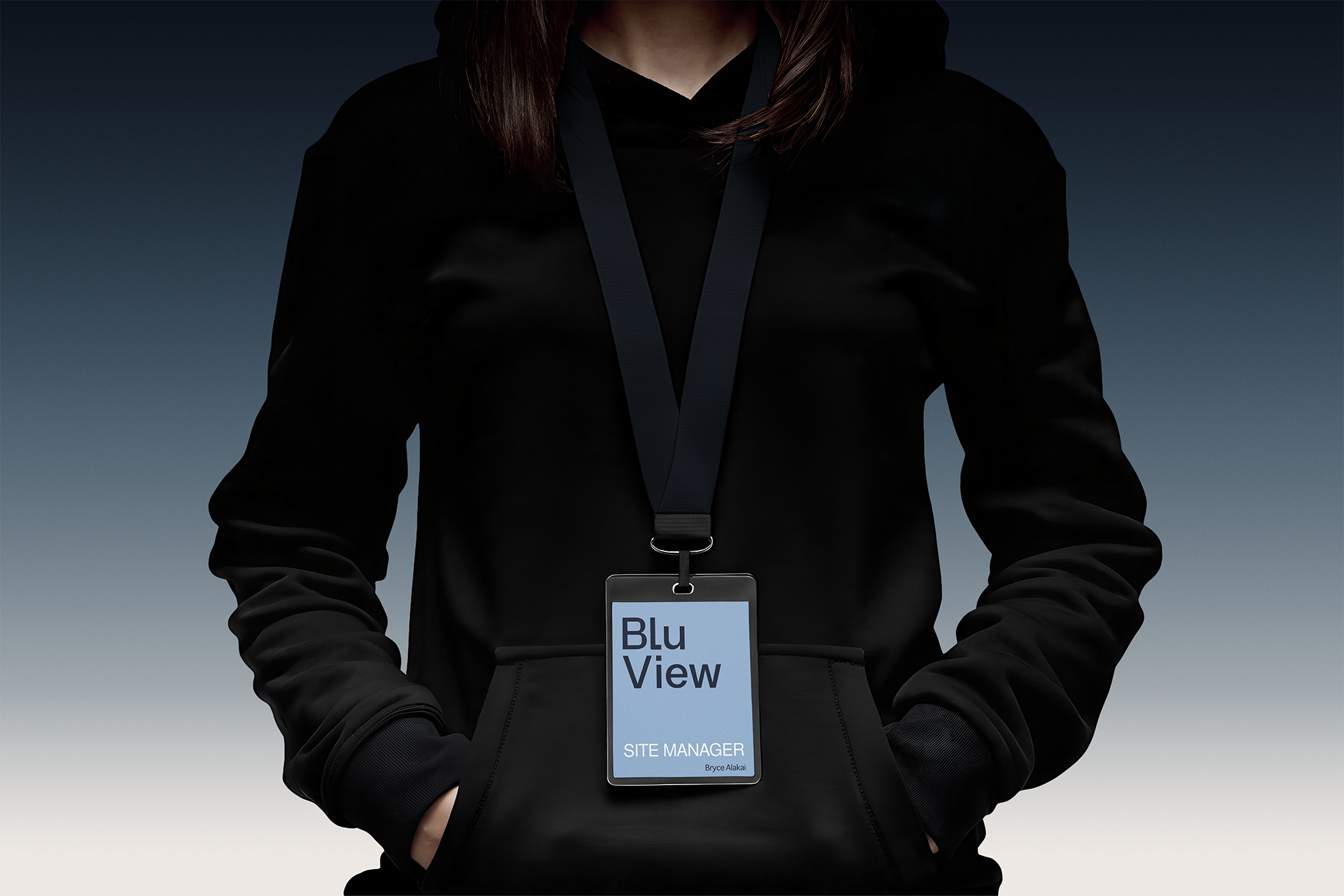 Person wearing black jacket and black lanyard with badge that reads "Site Manager" and "Bryce Alakai" against a dark sky background.