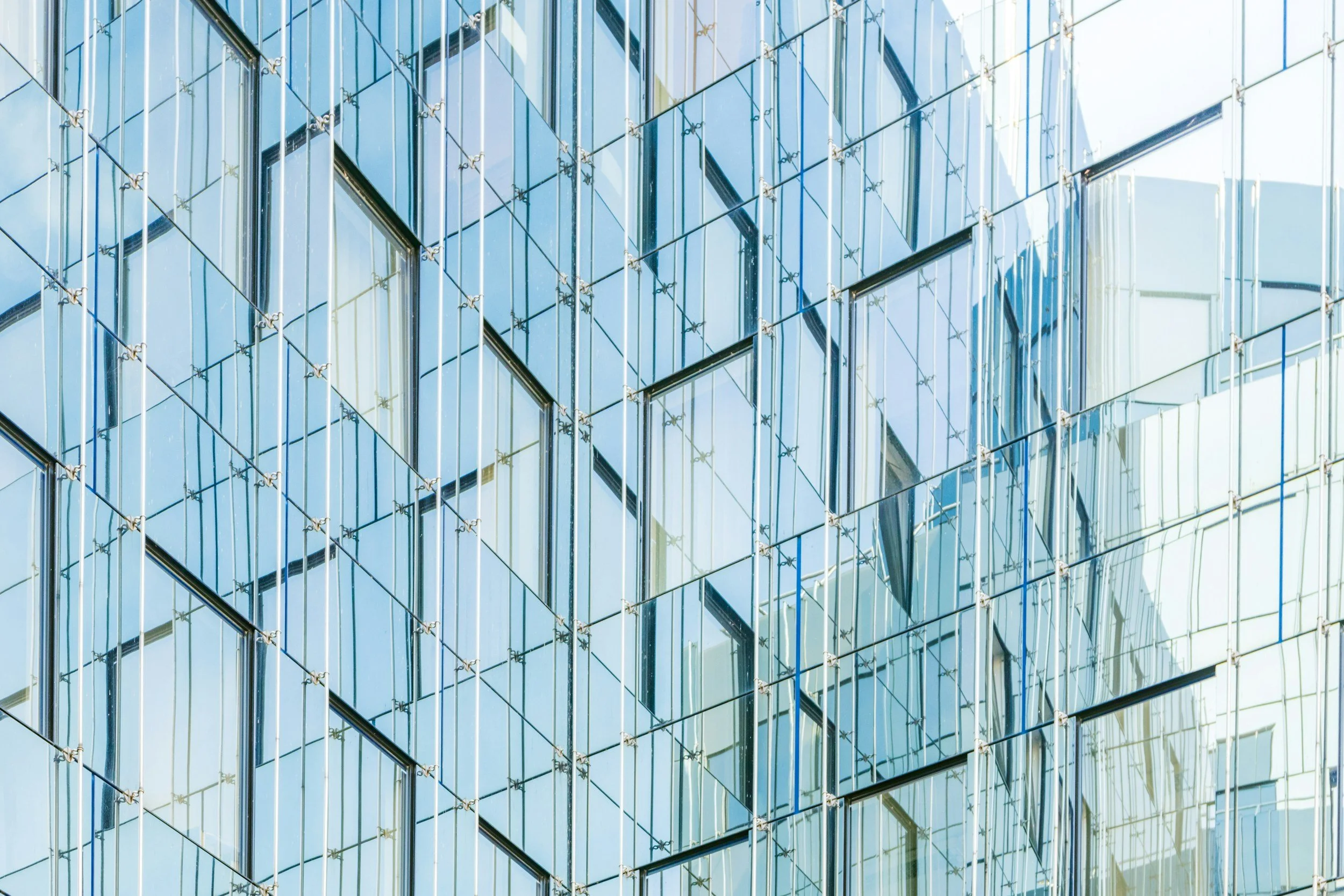 Close-up view of a modern building's glass exterior with reflective windows and metal framework.