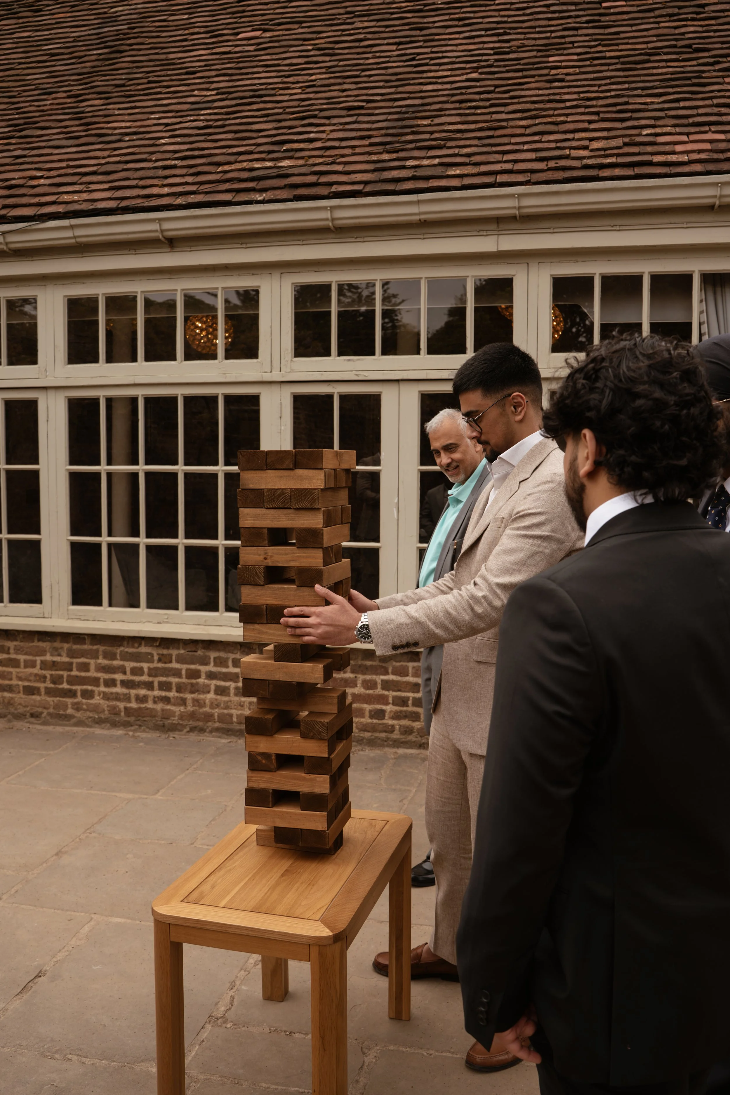 People dressed in suits playing a large outdoor Jenga game