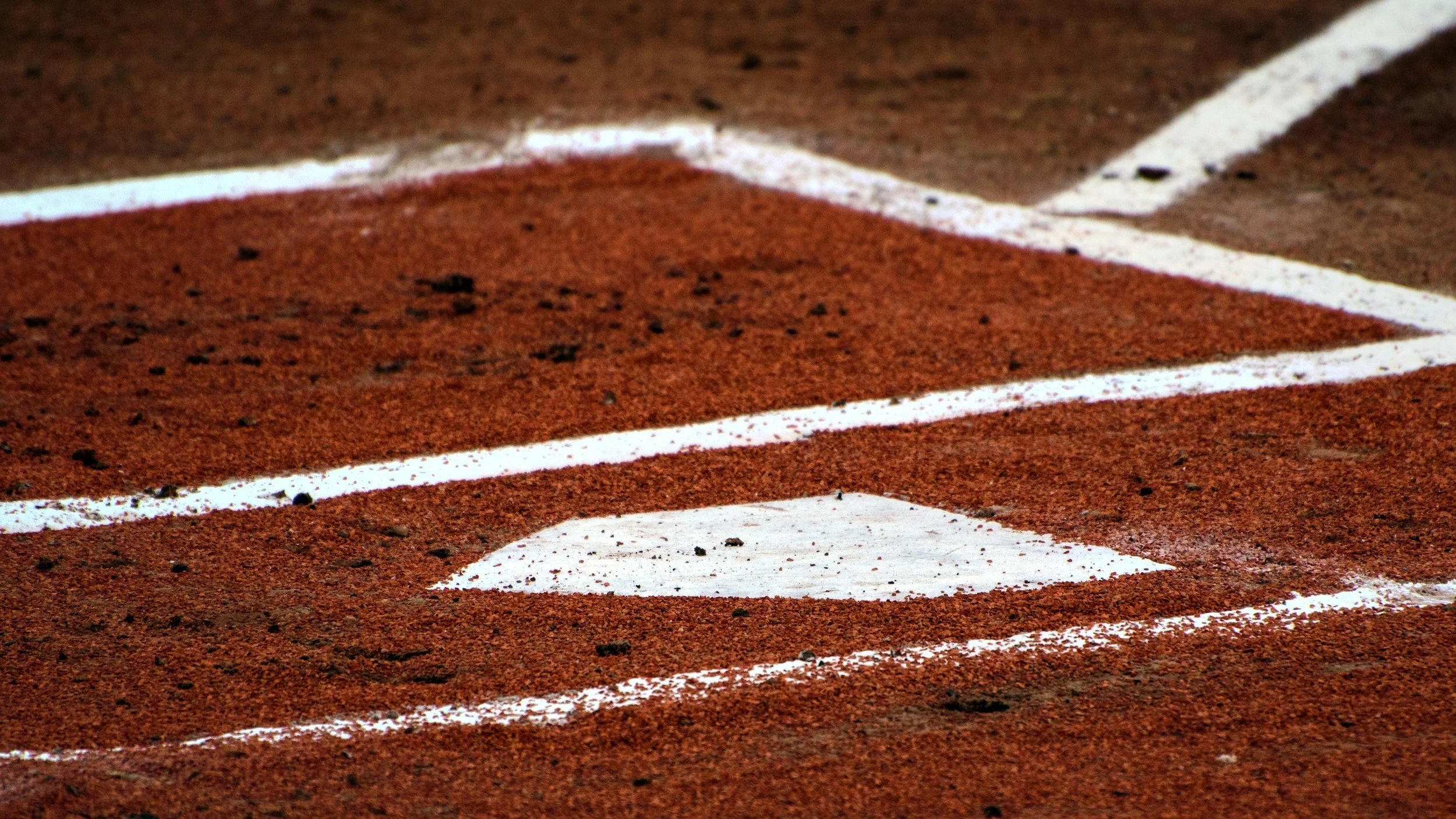 Close-up of a running track with white lane markings and a reddish-brown surface.