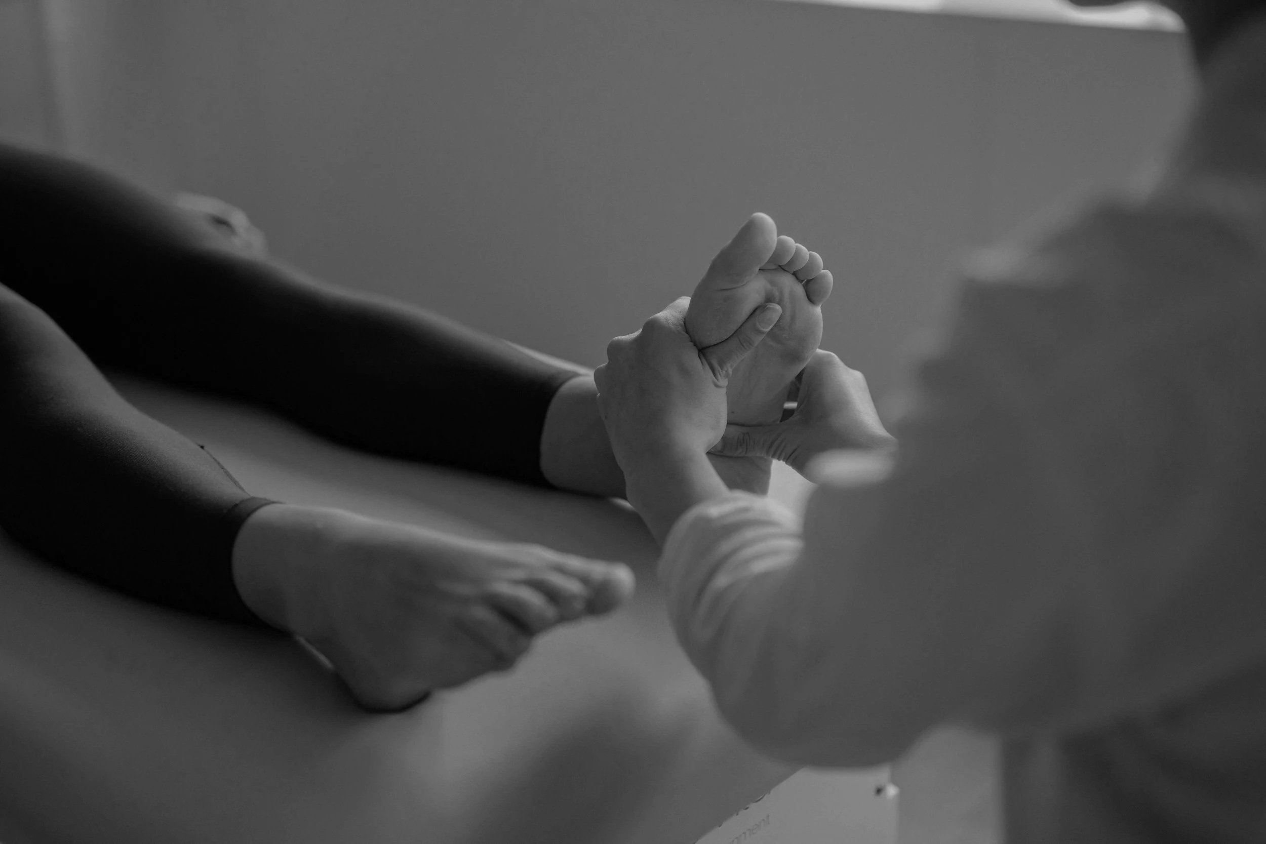 Close-up of two hands holding each other on a flat surface, with a blurred background and a computer monitor partially visible.
