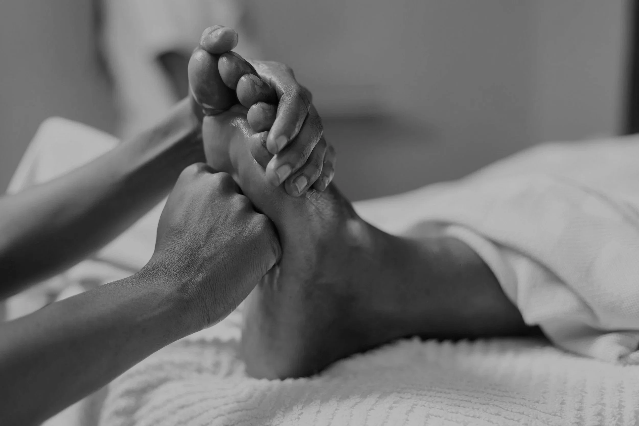 Black and white photo of a person's hand holding another person's hand gently.
