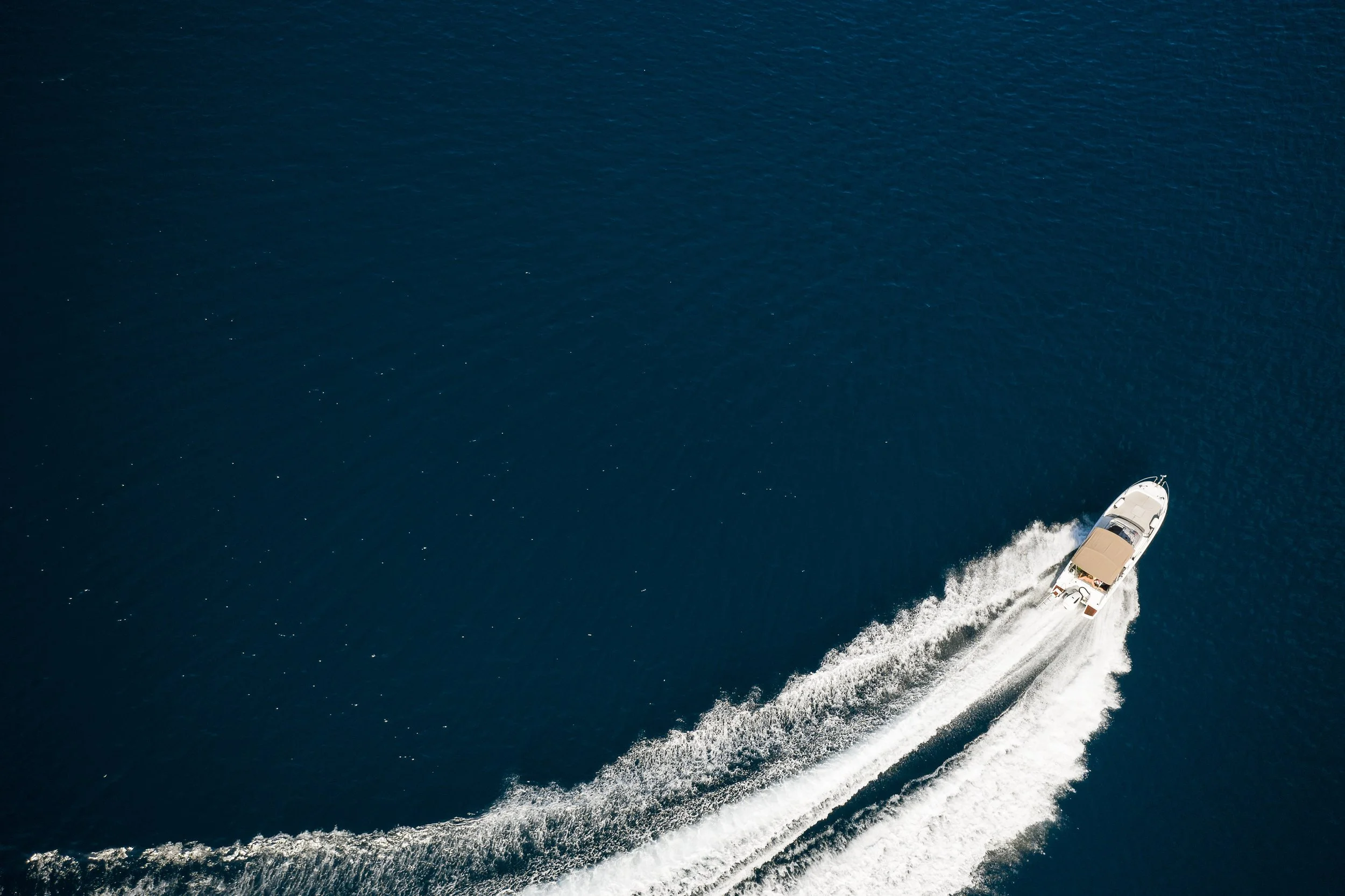 A motorboat speeding across deep blue water, leaving white wake behind.