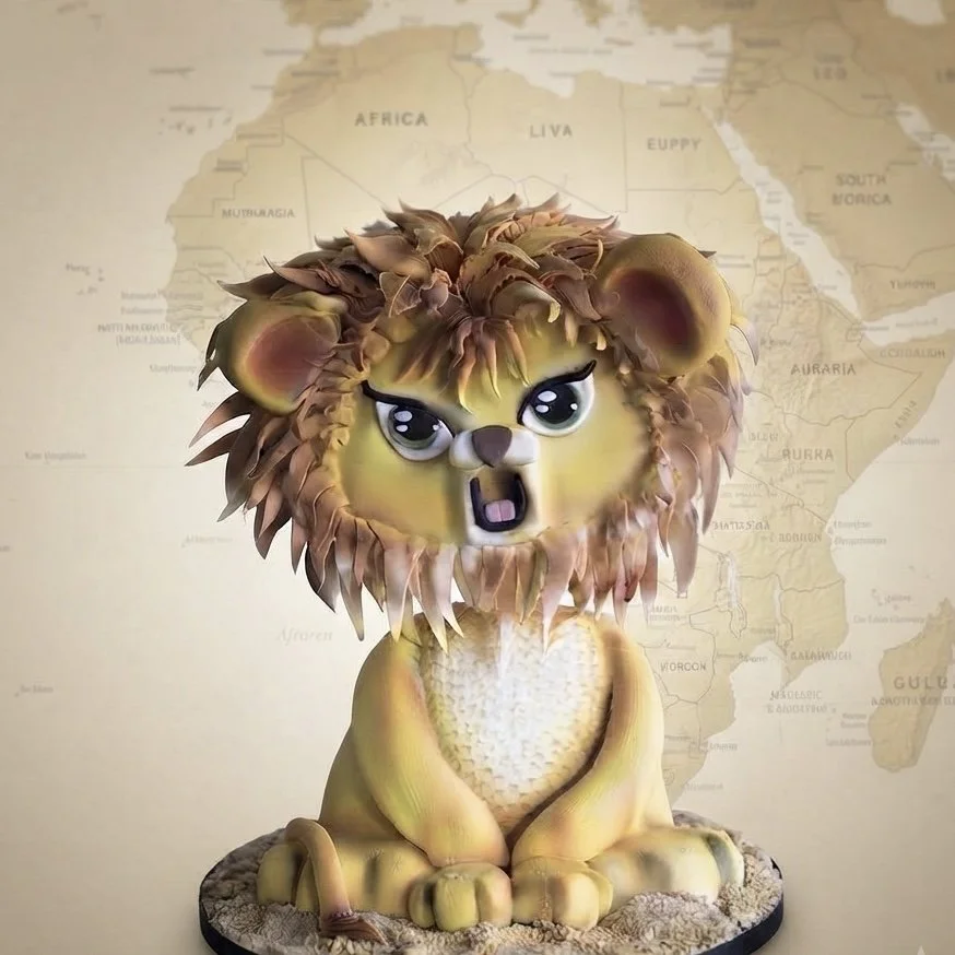 A lion sculpture with a cartoonish face and a detailed mane, sitting on a textured base in front of a map of Africa.