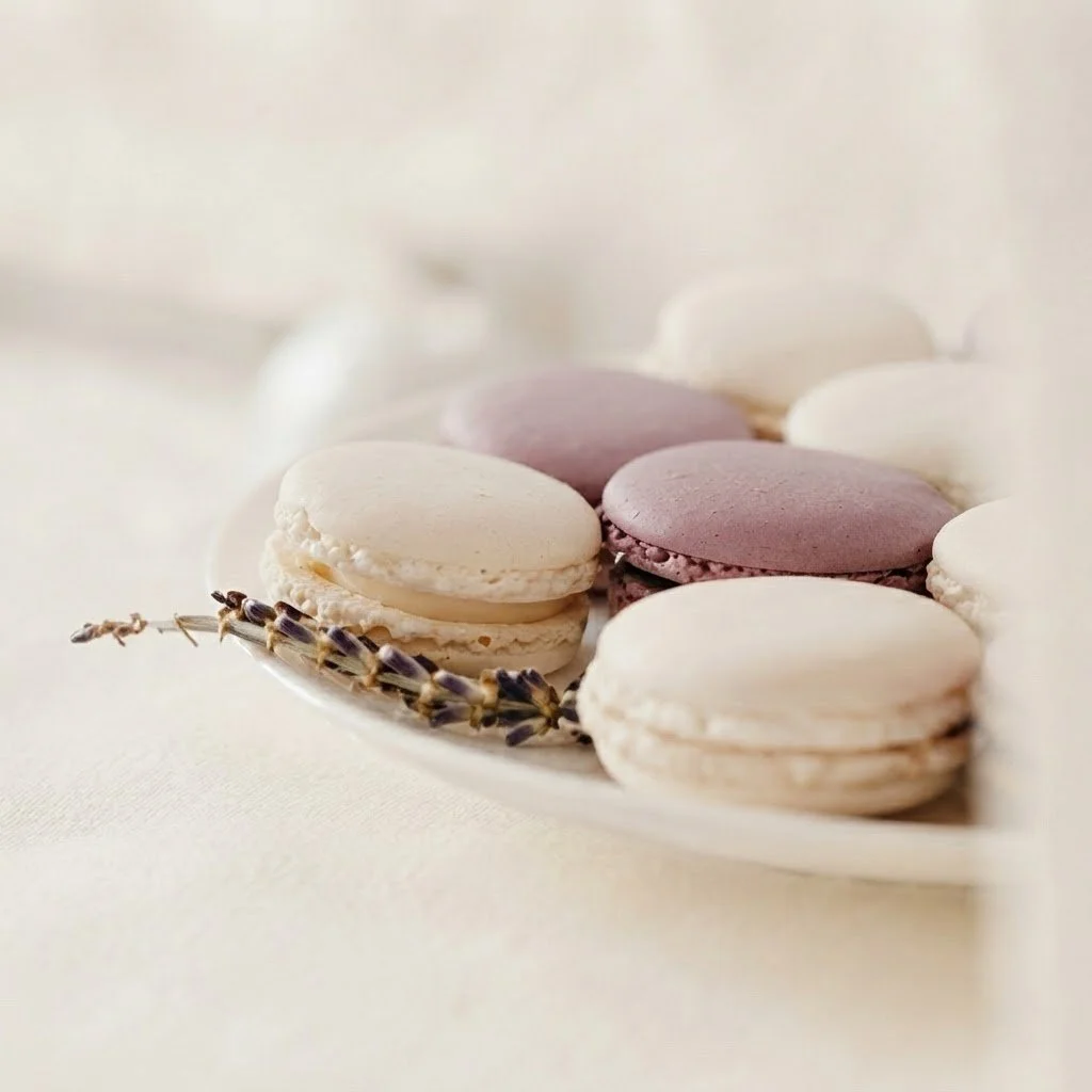 A silver tray with lavender and vanilla macarons and sprigs of lavender.