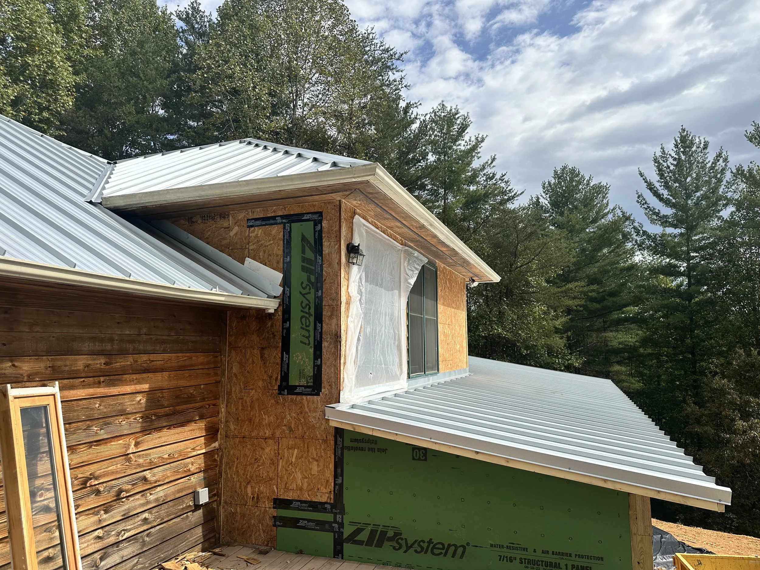 Standing seam metal roof installation on a custom home under construction by Modern Edge Builders in Western North Carolina.