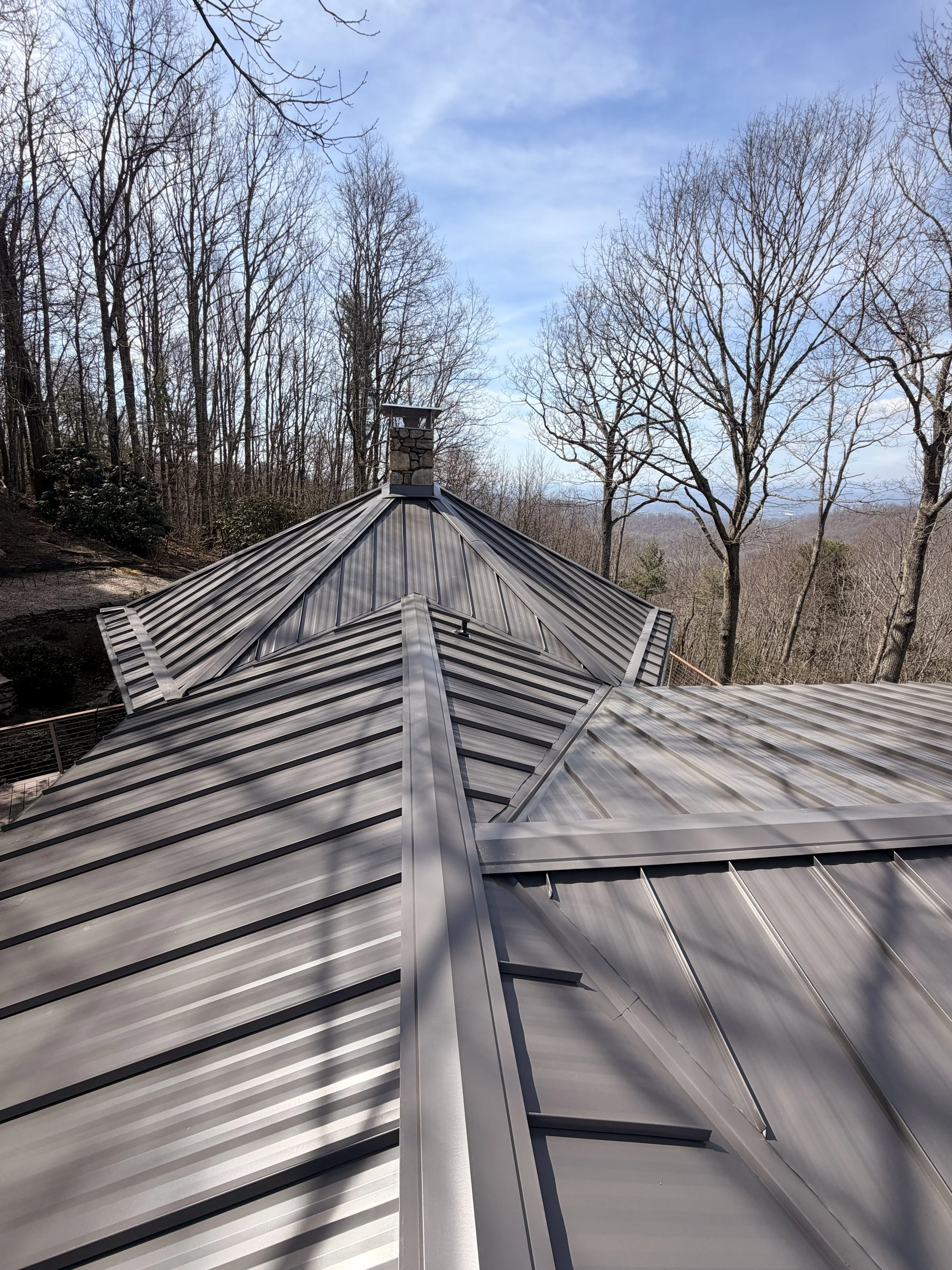 Standing seam metal roof installation on a custom mountain home featuring precision ridge details and premium metal roofing craftsmanship.