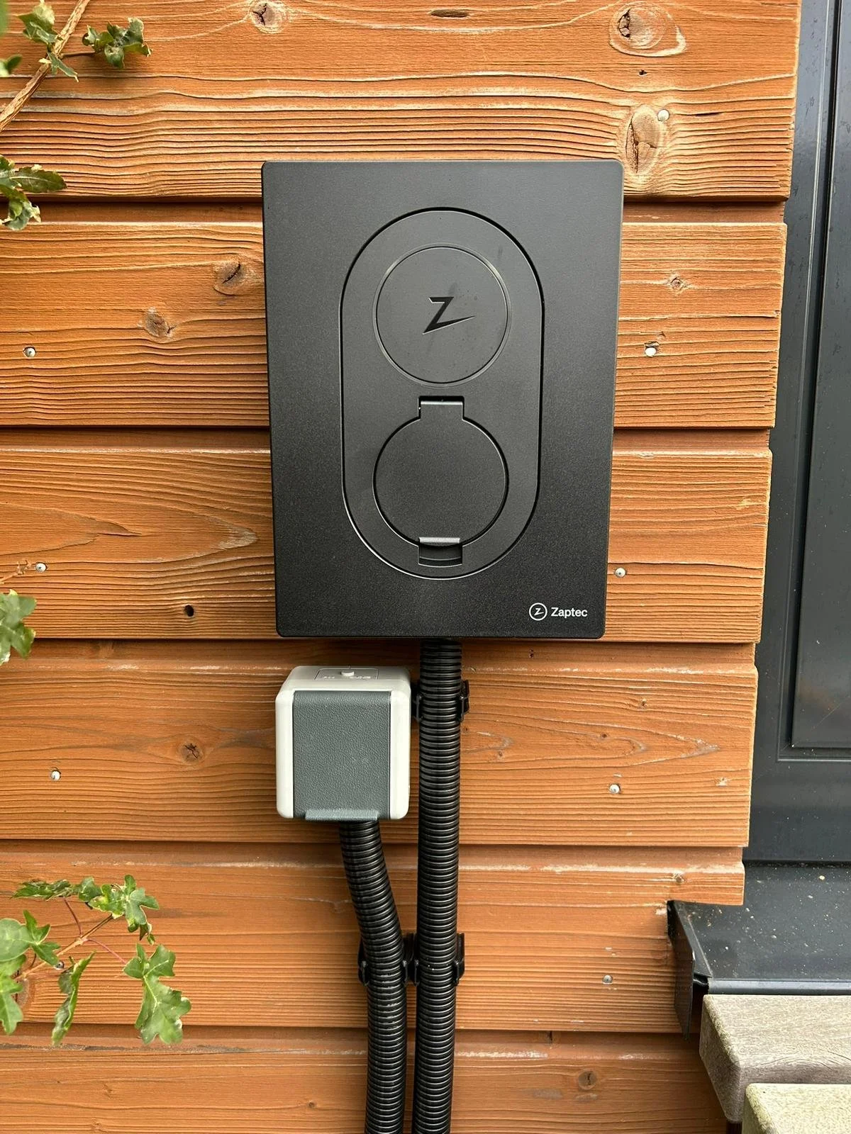 Elektrische buitenstopcontacten met afsluitdeksel op houten wand, merk Zaptec.