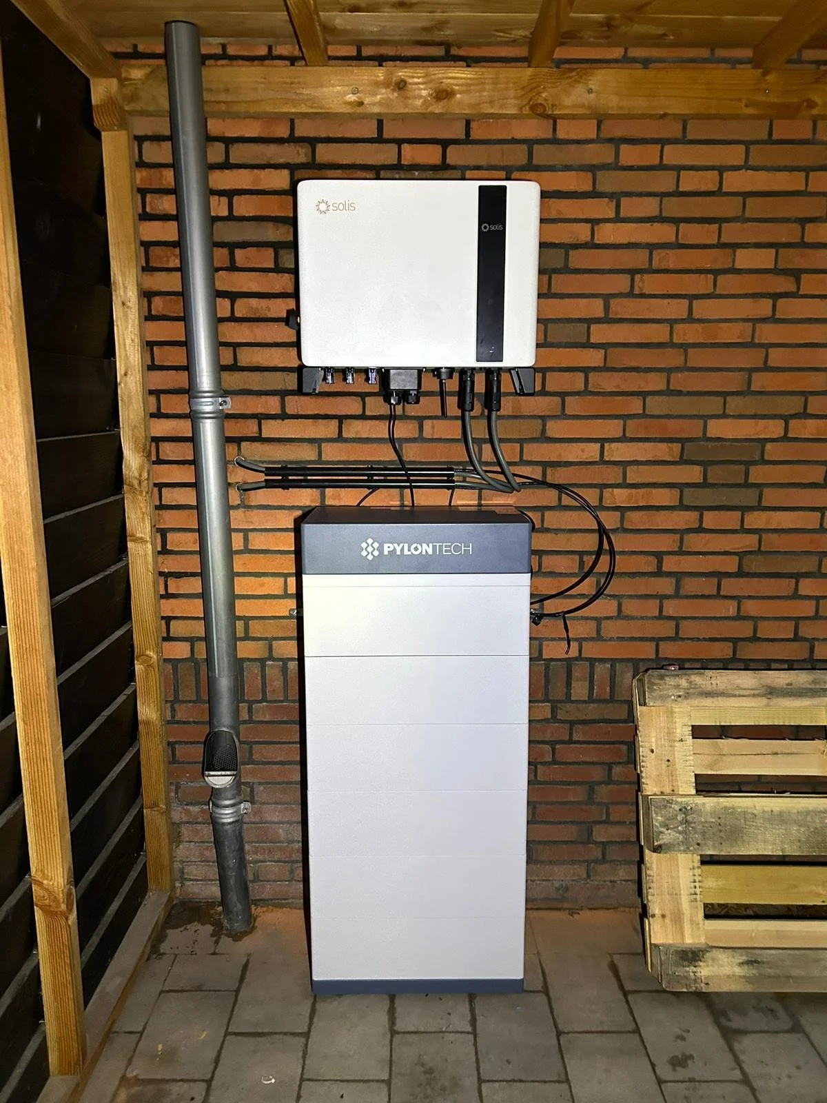Elektrische thuisbatterij van het merk Pylontech met Solis hybride omvormer, geïnstalleerd in een garage met bakstenen muur.
