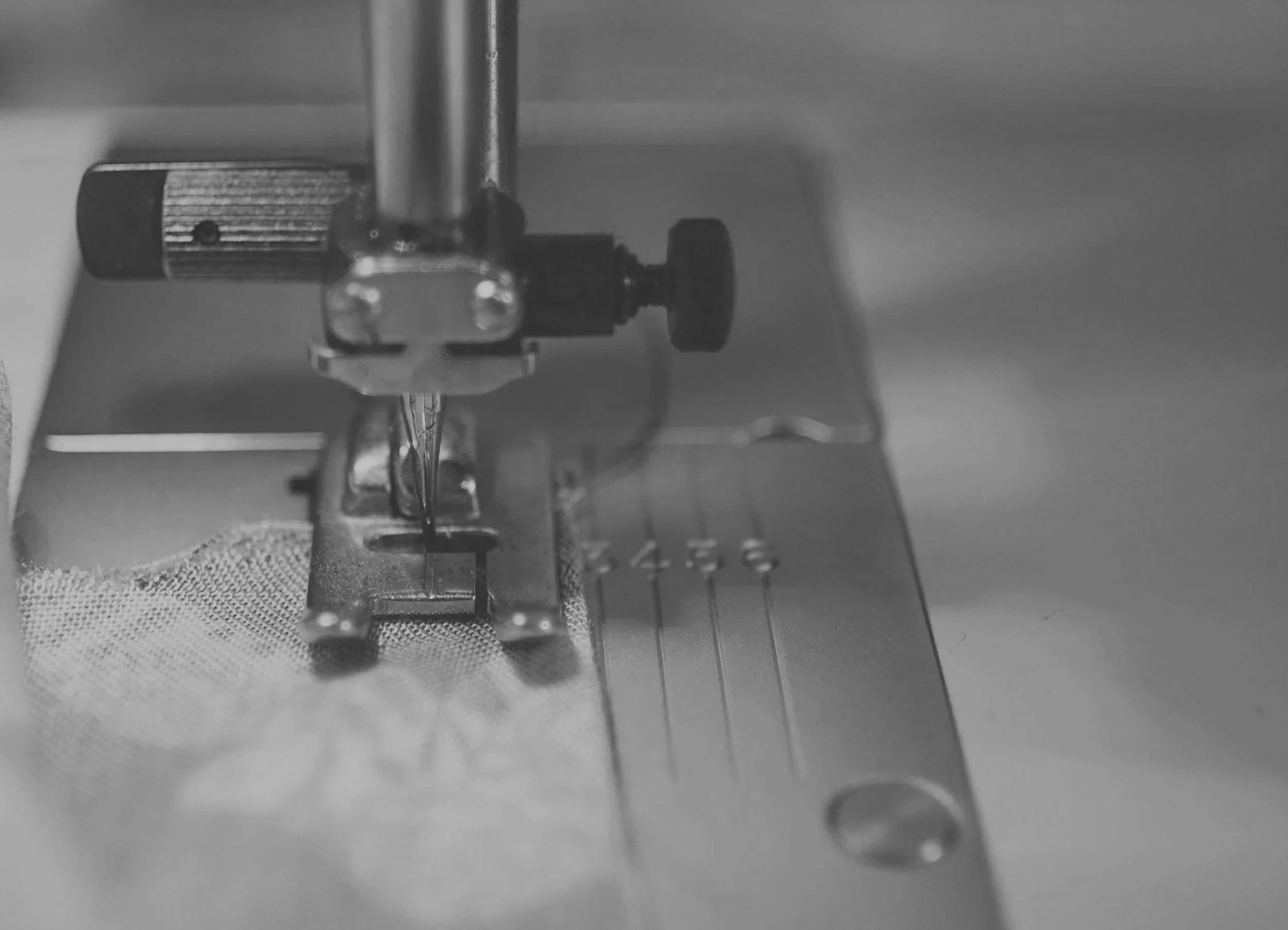 Close-up view of a sewing machine's needle and presser foot as it stitches fabric.