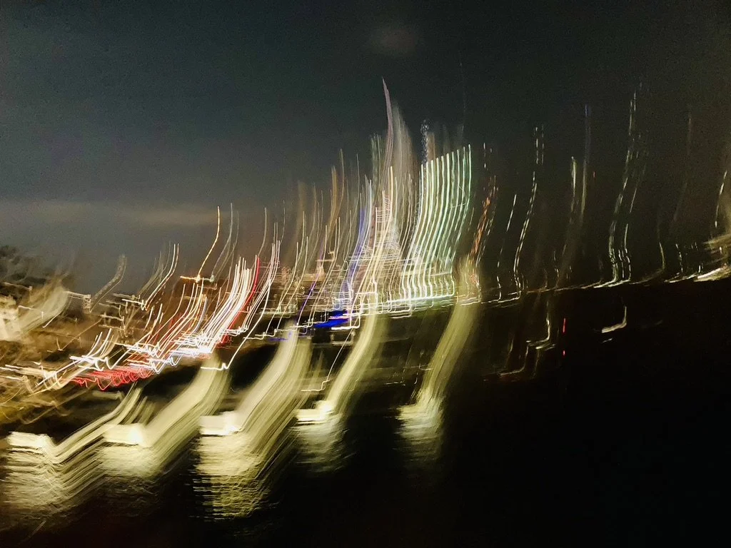 Abstract photograph of city lights at night, with light streaks and blurry reflections.
