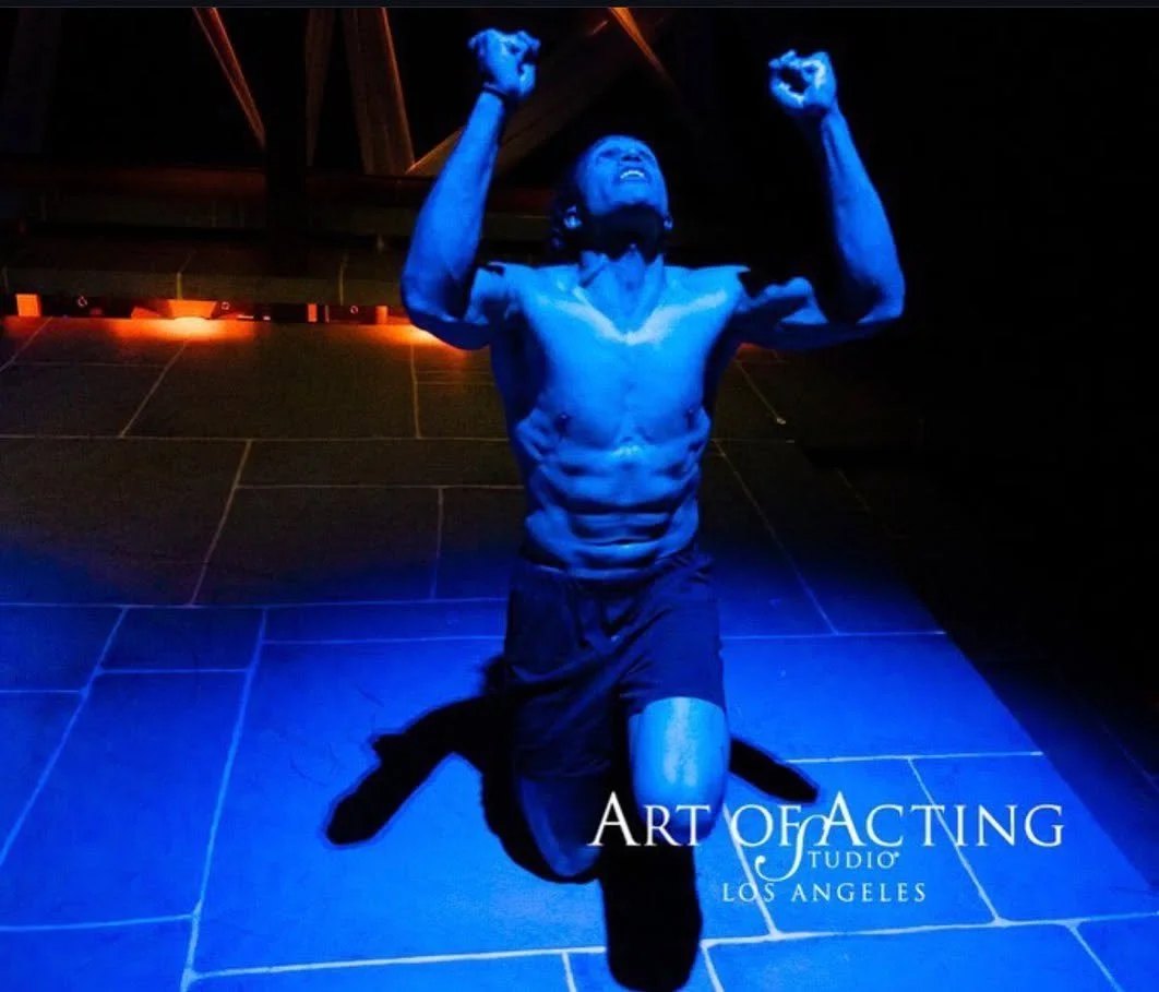 A man kneeling with fists clenched and arms raised, illuminated by blue light, with the text 'Art of Acting Studio Los Angeles' in the bottom right corner.