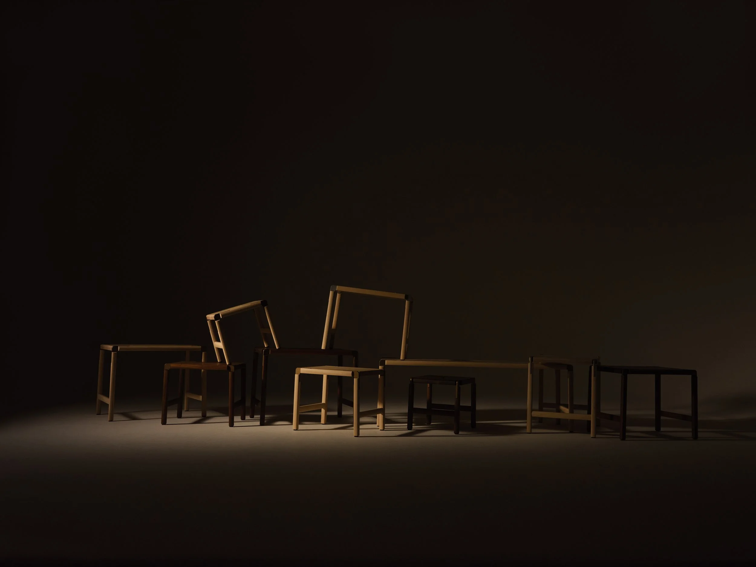 Multiple wooden chairs arranged on a stage with a dark background.