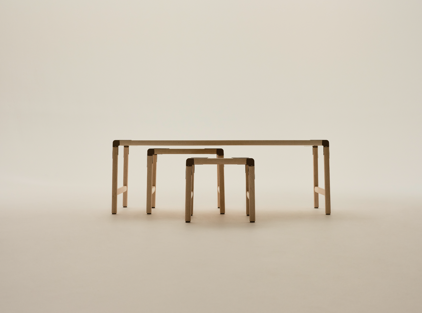 Four wooden tables of varying heights arranged in ascending order from smallest to largest, set against a plain, light-colored background.