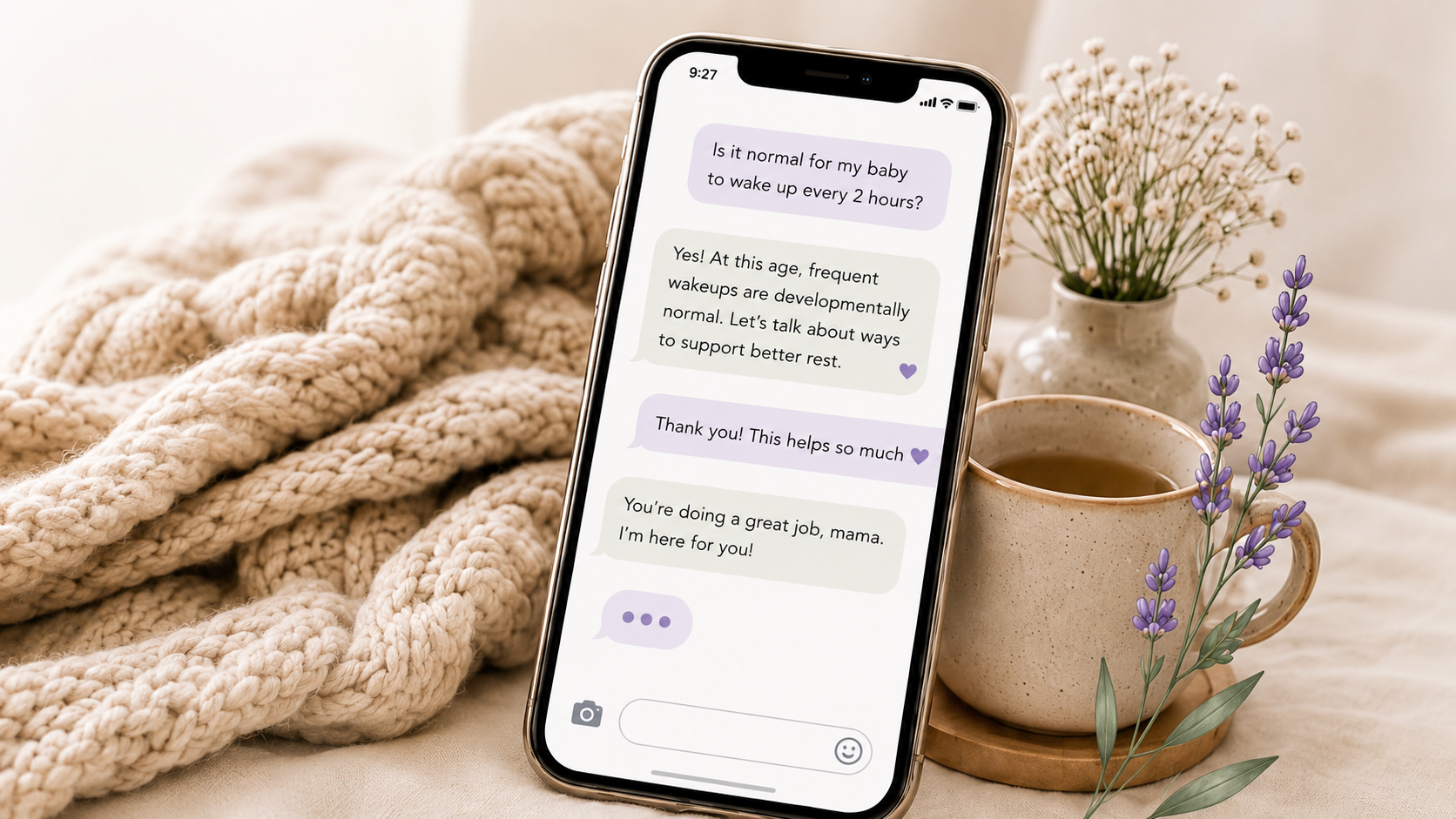 Smartphone displaying a text message conversation, resting on a cozy blanket next to a cup of coffee and small vases of purple lavender and white baby's breath flowers.