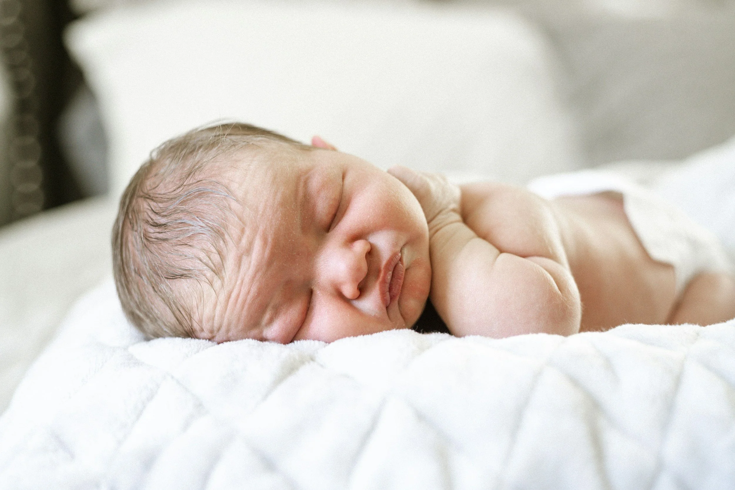 A sleeping newborn baby lying on a white blanket.