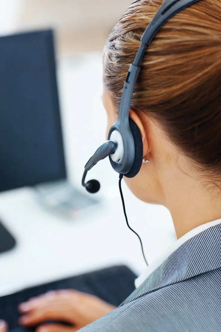 Une femme portant un casque de communication, travaillant devant un ordinateur.