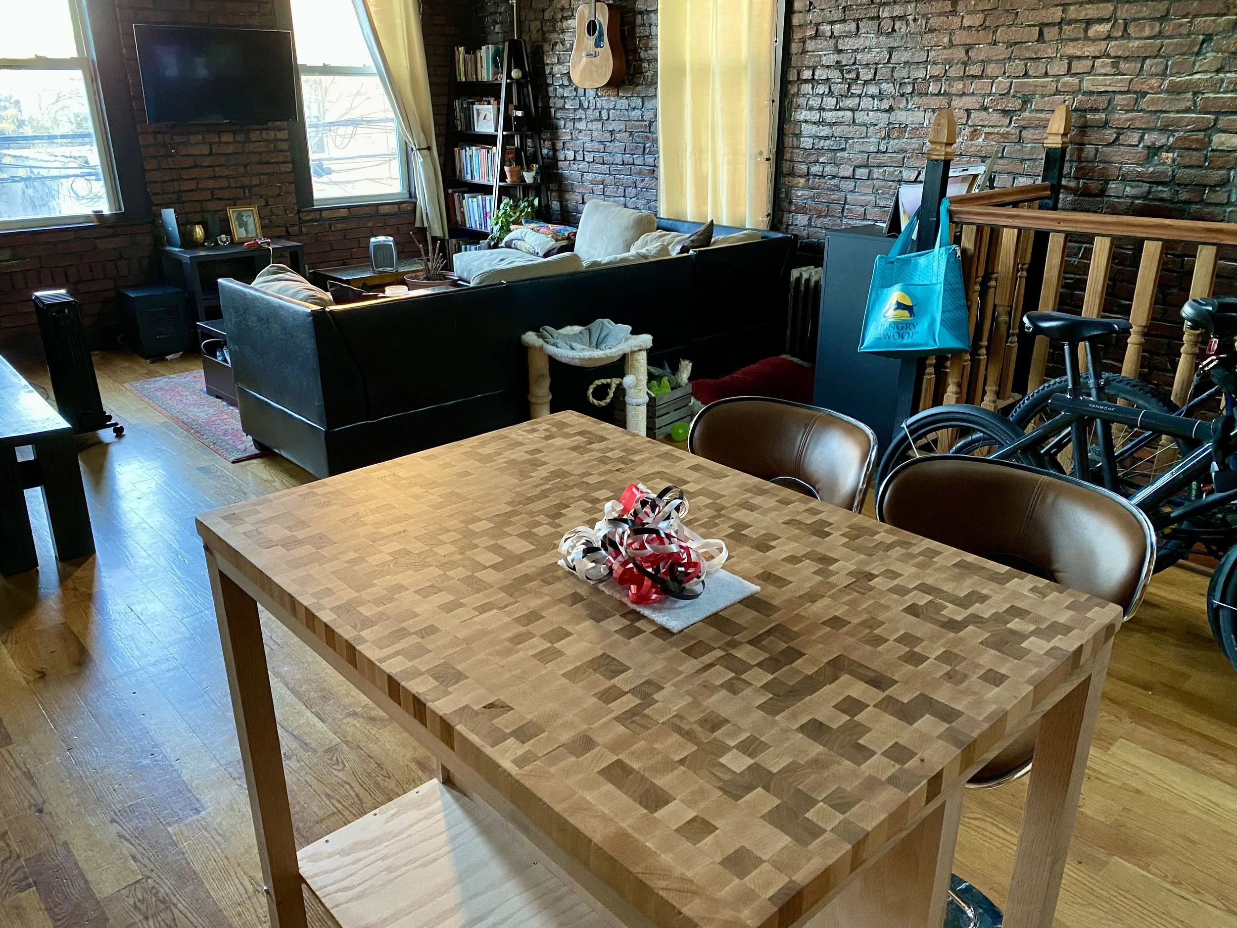 A cozy living room with brick walls, large windows, with a wooden butcher block island with modern style