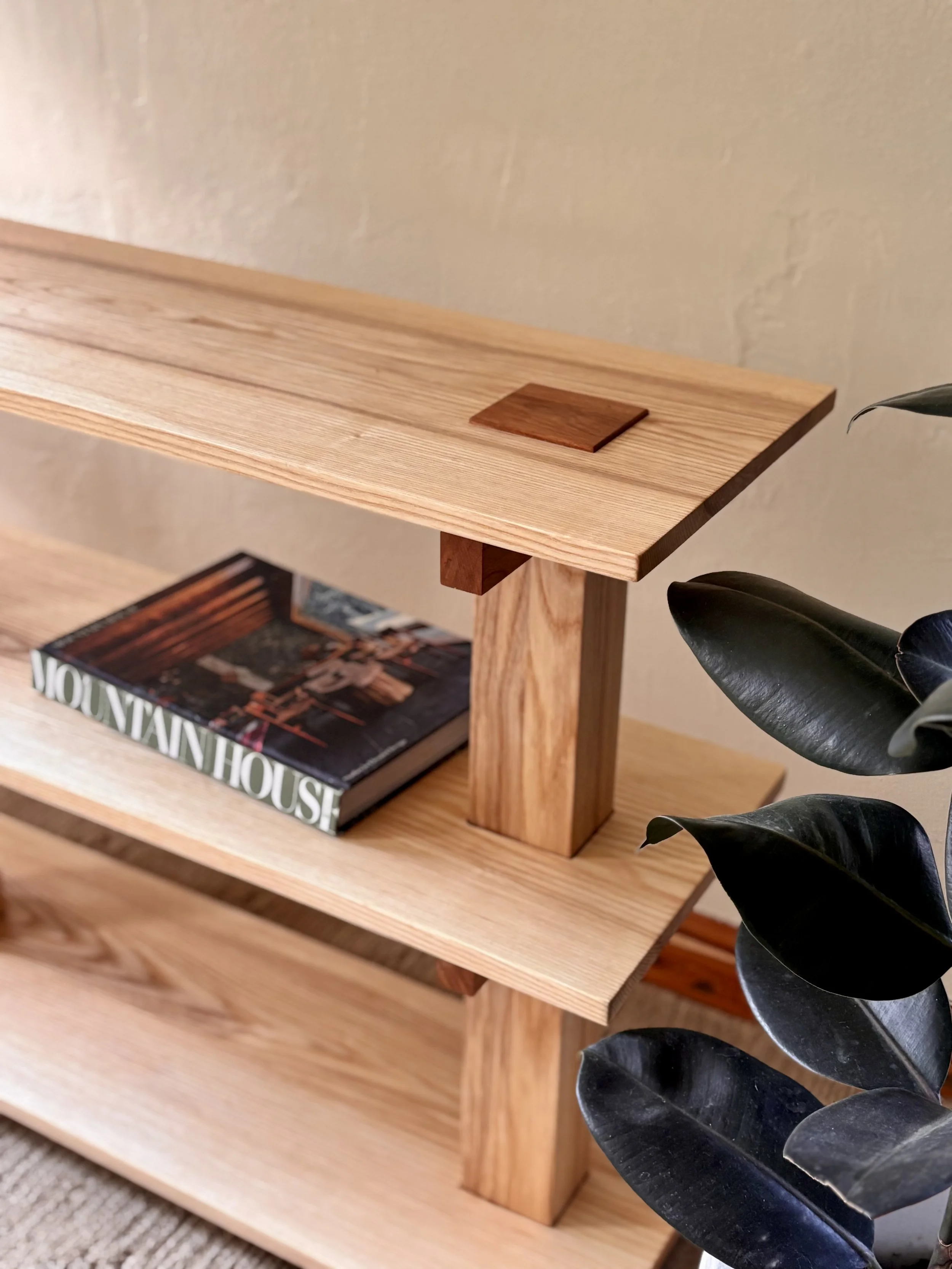 A Scandinavian-style three-tier wooden bookshelf made of ash and cherry hardwood.