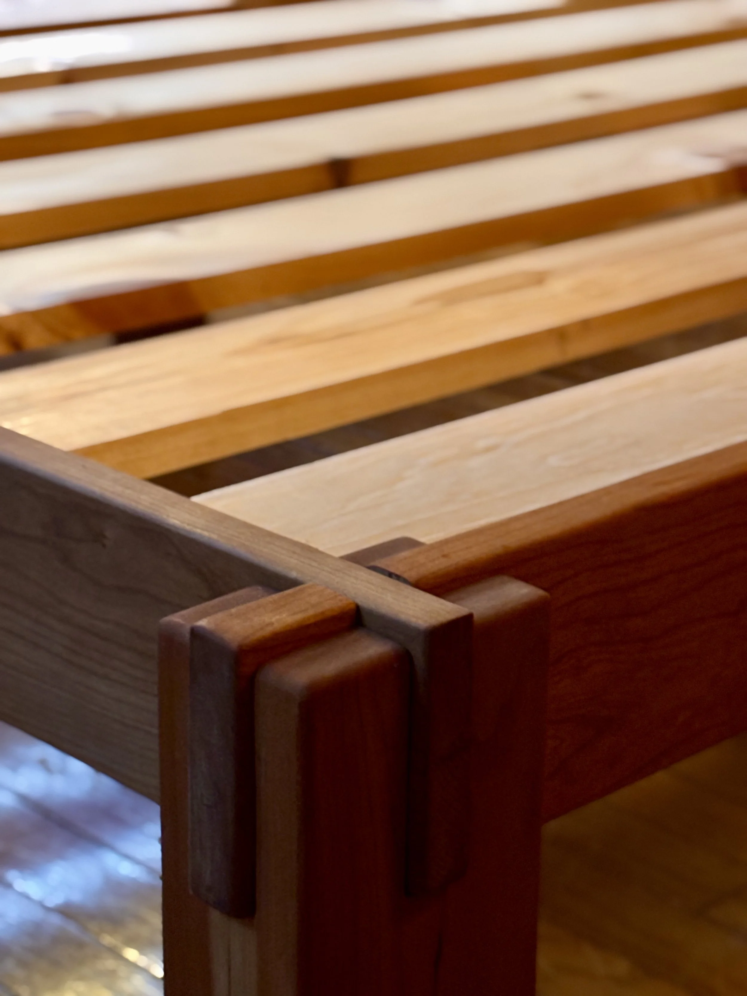Close-up of a wooden chair with slatted backrest and armrest details.