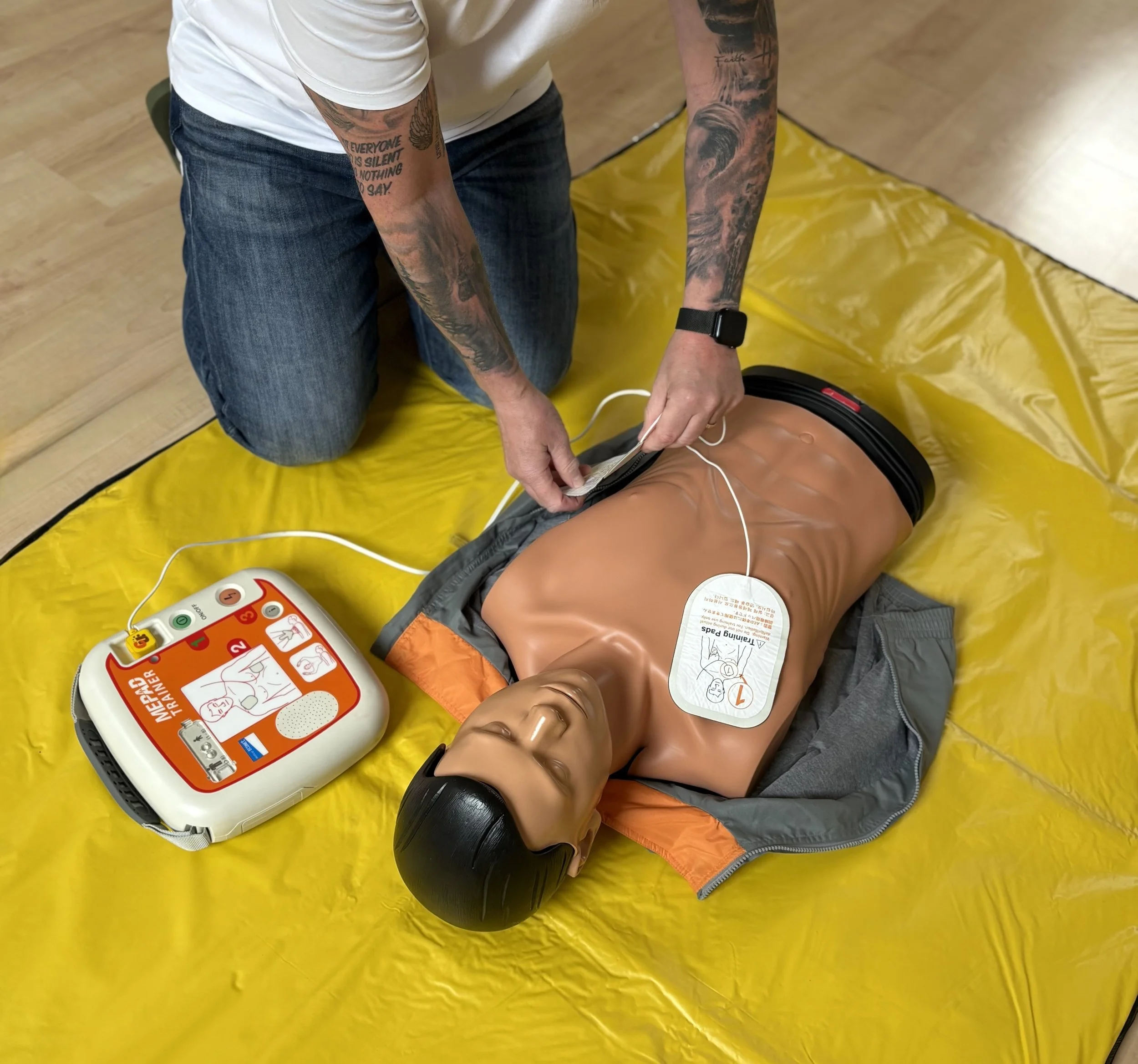 „Stefan Reinhard legt einer Trainingspuppe die AED‑Pads an.
