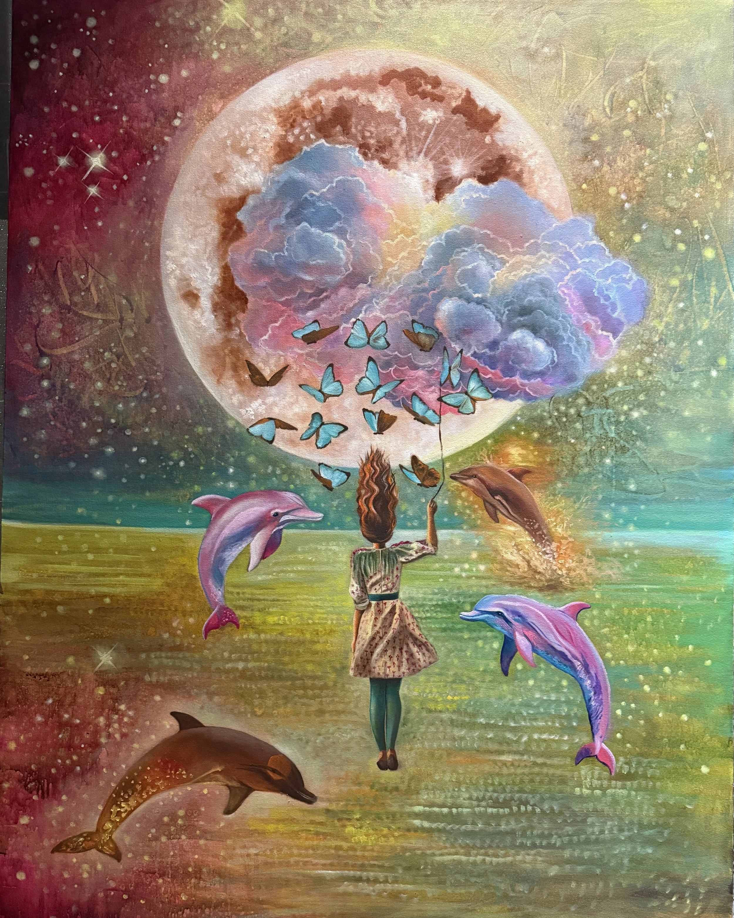 A colorful fantasy scene with a woman standing in water, dolphins jumping around her, and butterflies flying above. A large moon or planet is in the background with clouds and stars, creating a dreamy, cosmic atmosphere.