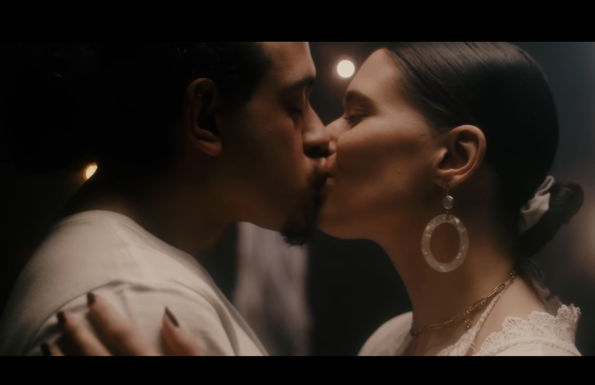 A close-up scene of a man and woman about to kiss, with their foreheads touching and eyes closed, in a dimly lit setting.
