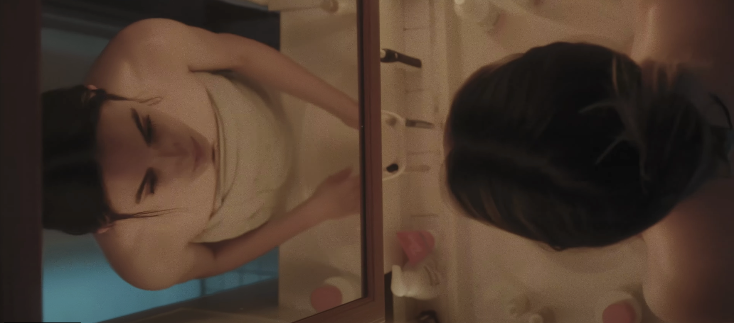 A woman looking into a mirror in a bathroom
