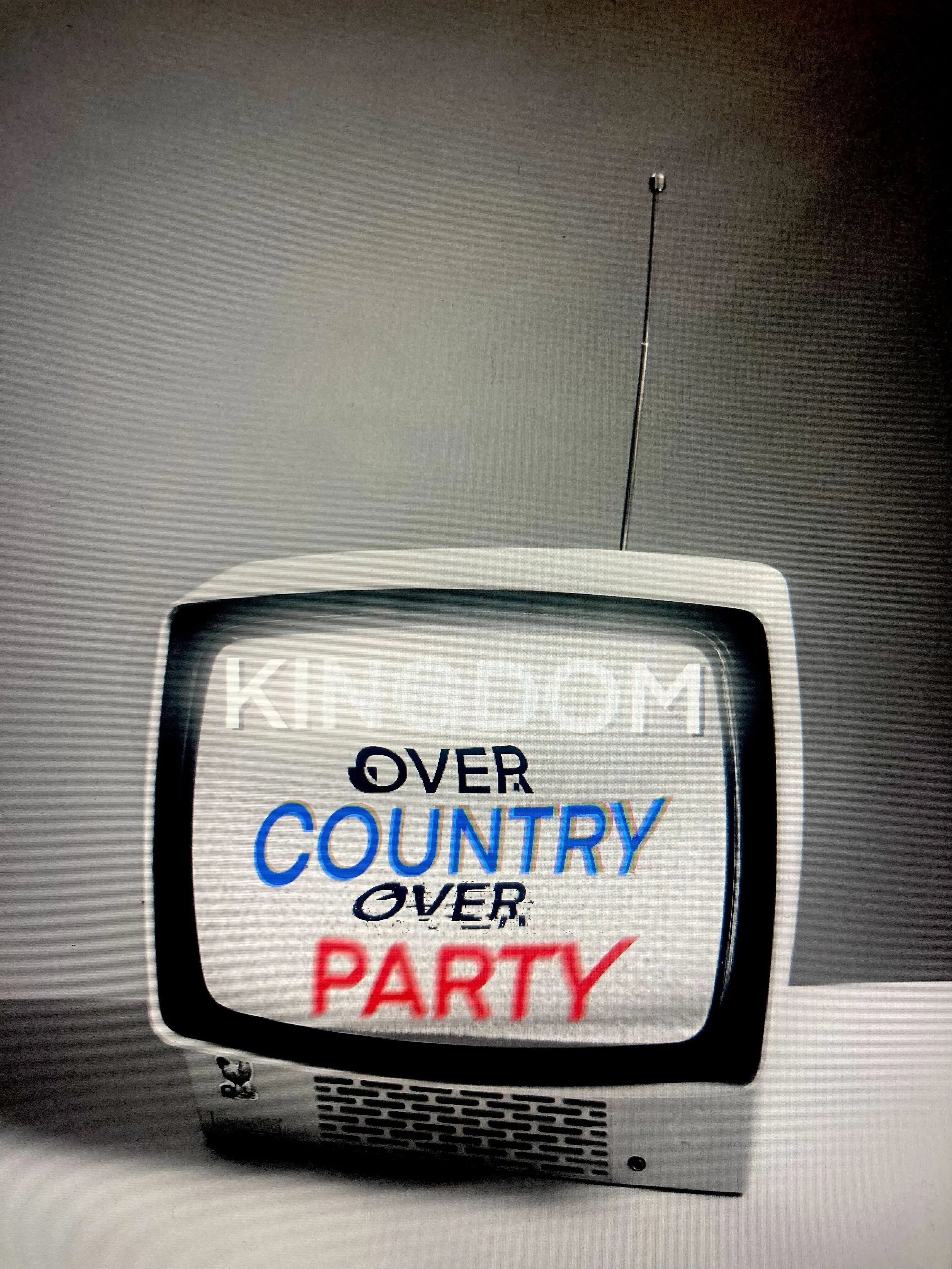 A portable speaker with a sticker that reads, 'KINDOM OVER COUNTRY OVER PARTY' in colorful text.