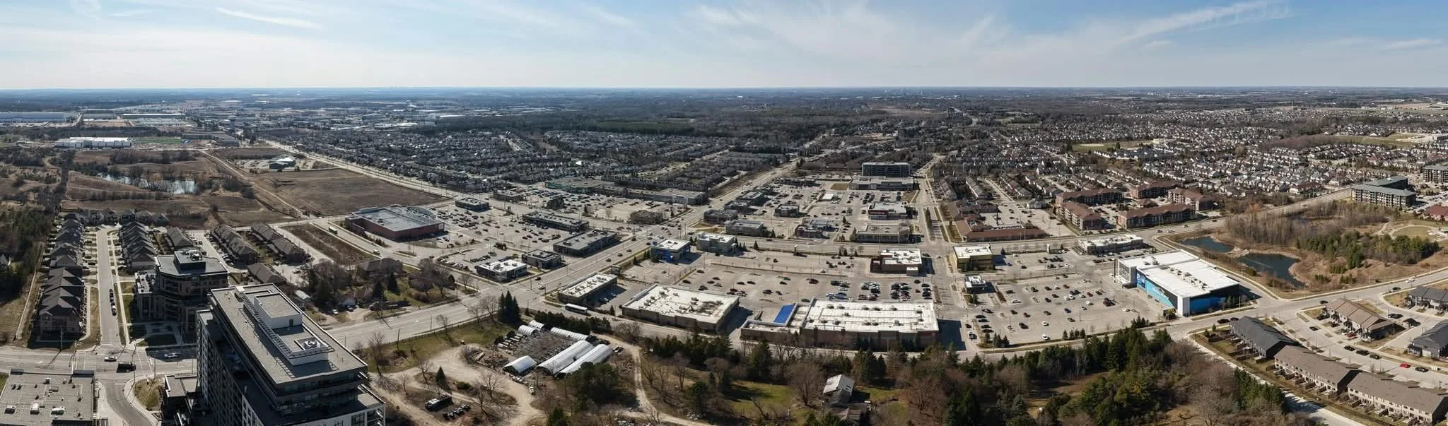 Aerial view of a suburban shopping center with parking lots and surrounding residential areas.