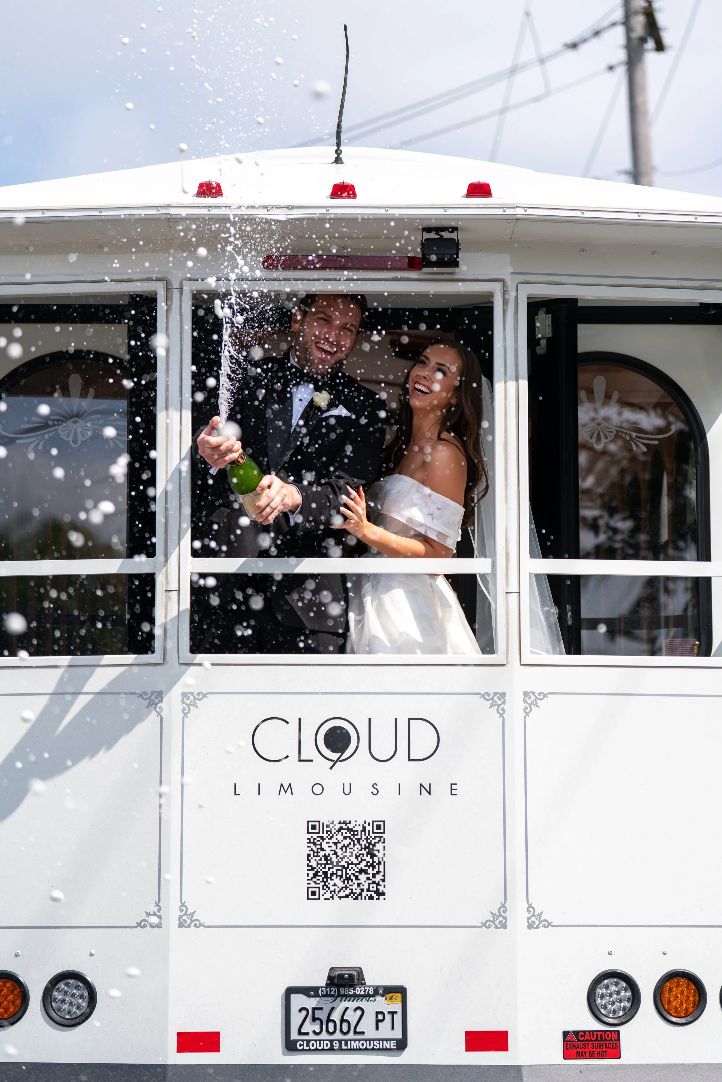 Happy bride and groom in a white limousine, celebrating with champagne, as snow falls around them.