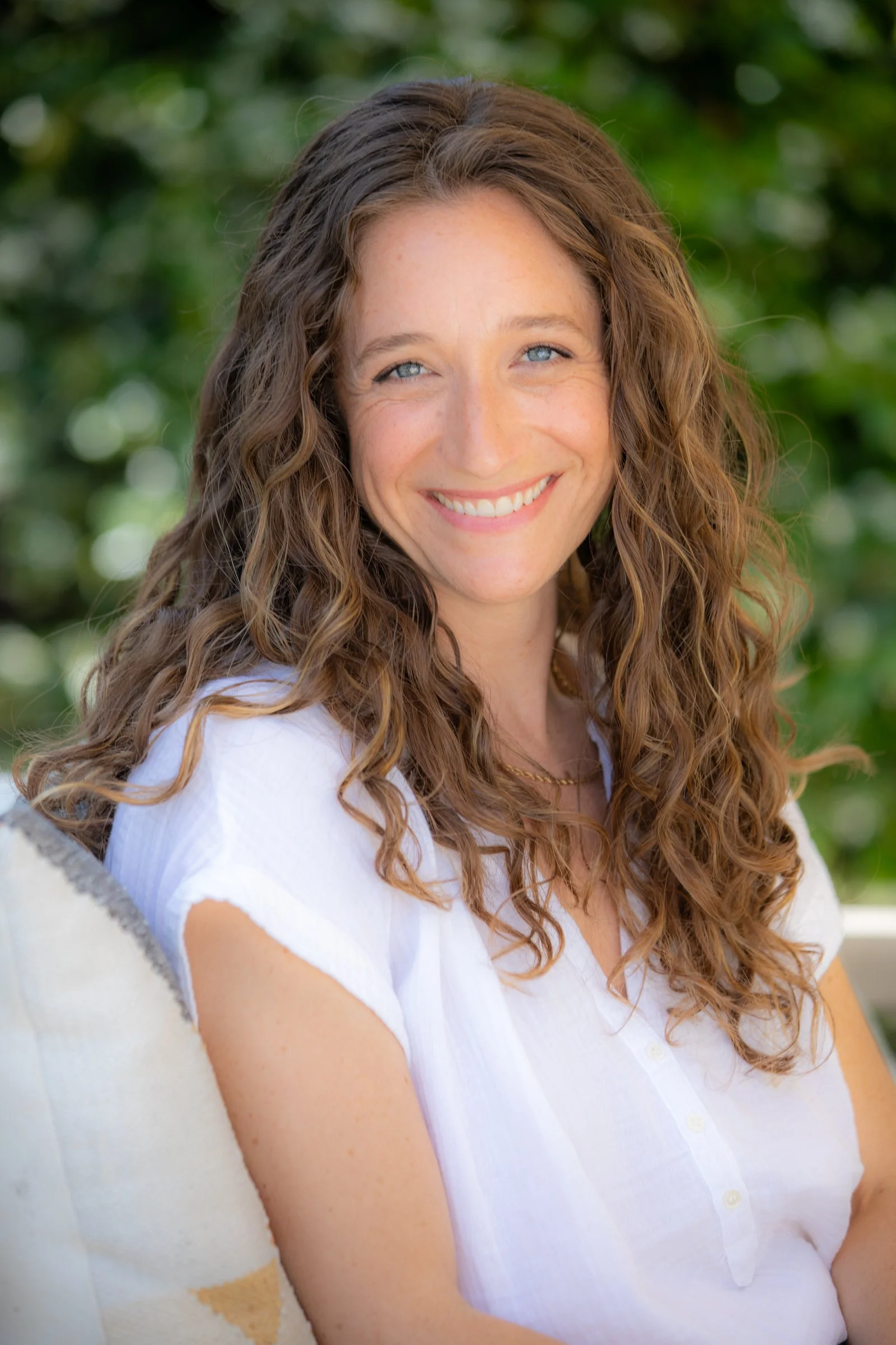 Julie Marx, a woman with long, curly brown hair and blue eyes smiling outdoors.