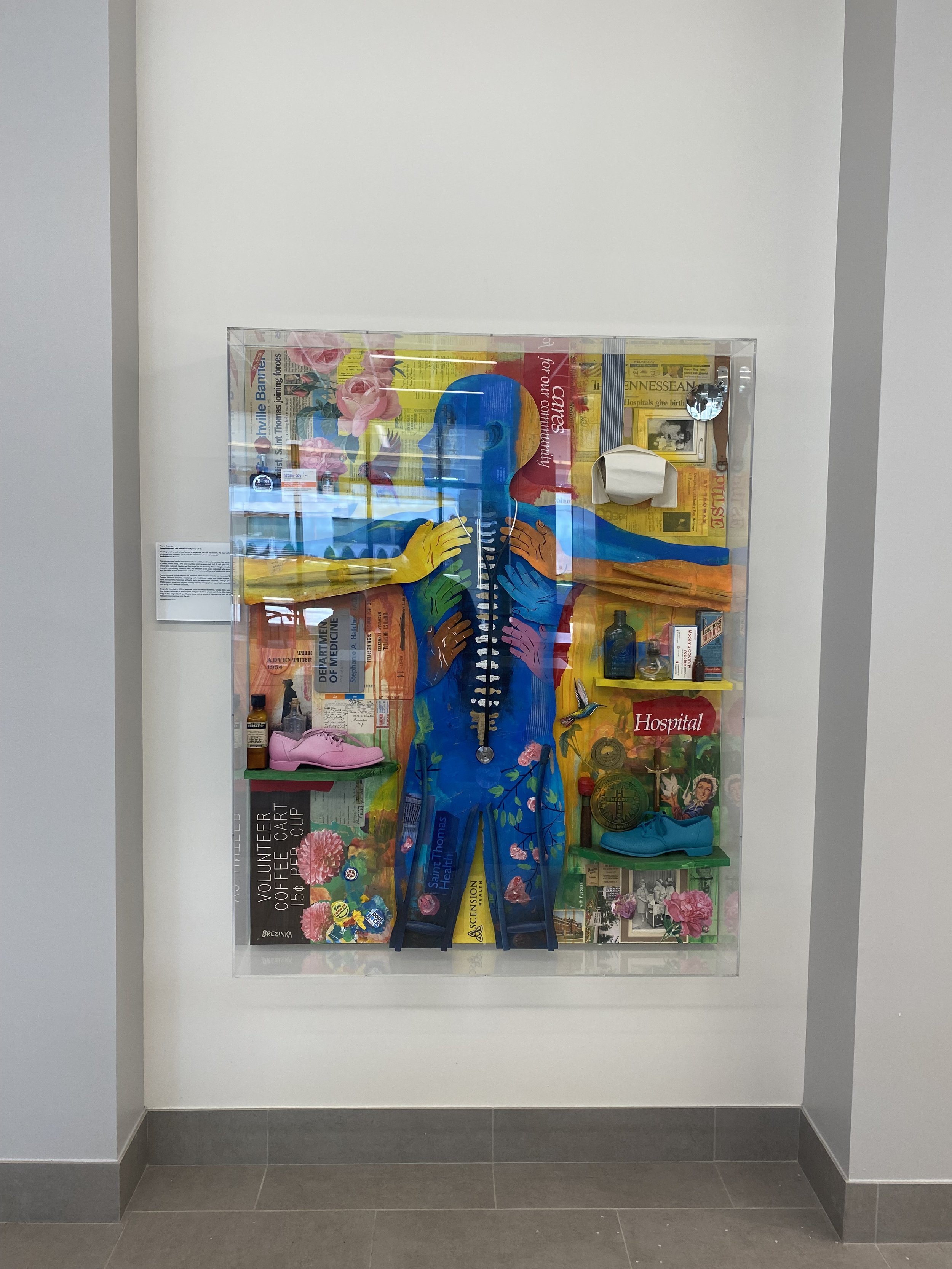 Colorful wall-mounted artwork protected by a clear acrylic display case.