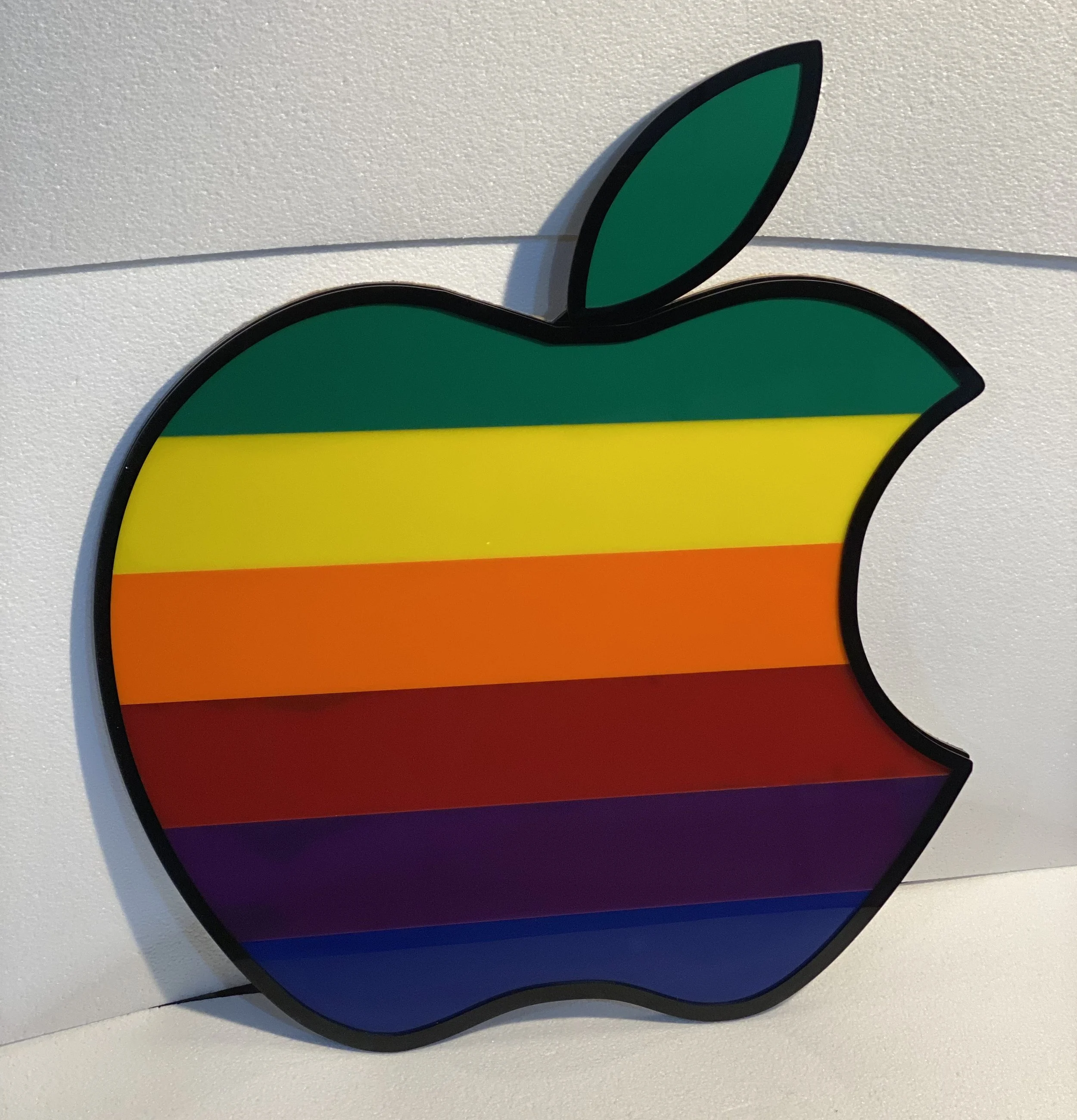 Close-up of a colorful rainbow-striped Apple logo on a white surface.