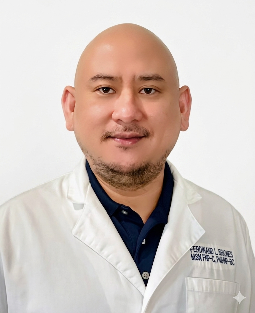 Portrait of a man with a shaved head and goatee, wearing a white lab coat and a dark collared shirt, against a plain white background.