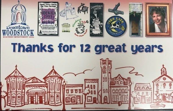 A sign with the message 'Thanks for 12 great years' featuring illustrations of a town skyline with historic buildings and a row of colorful magnets at the top, including a photo of a smiling woman.