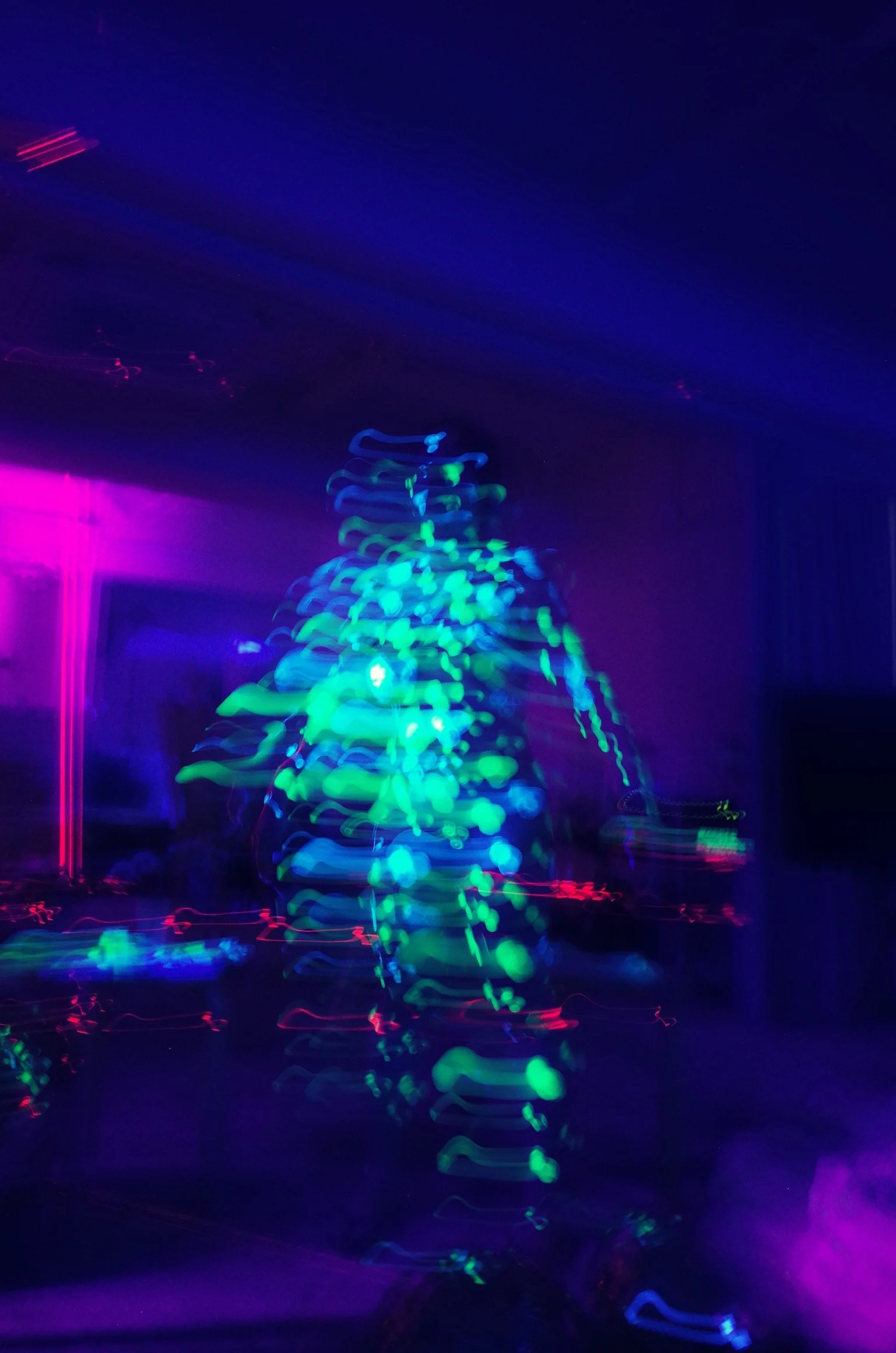 Colorful abstract light photo with neon pink, blue, and green lights creating blurred streaks and shapes in a dark setting.