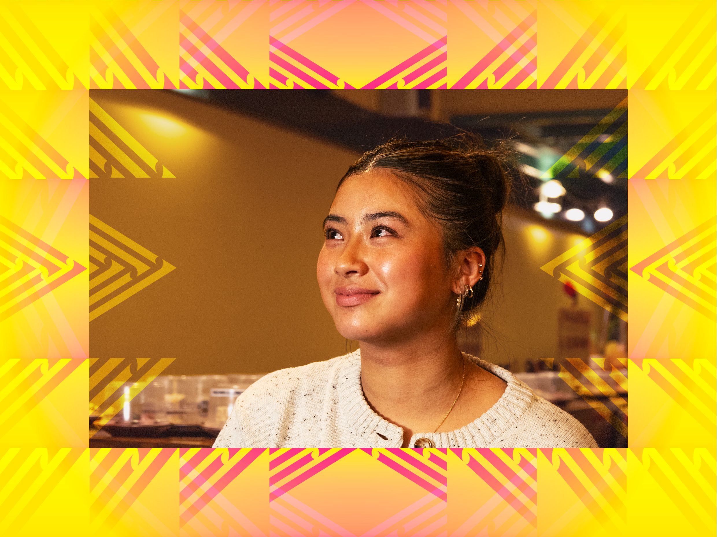 A picture of Phoebe from Catch Sushi Bar in Courtenay Place. She is a young woman with dark hair tied back, wearing a cream-colored sweater, smiling softly in a warmly lit indoor setting.