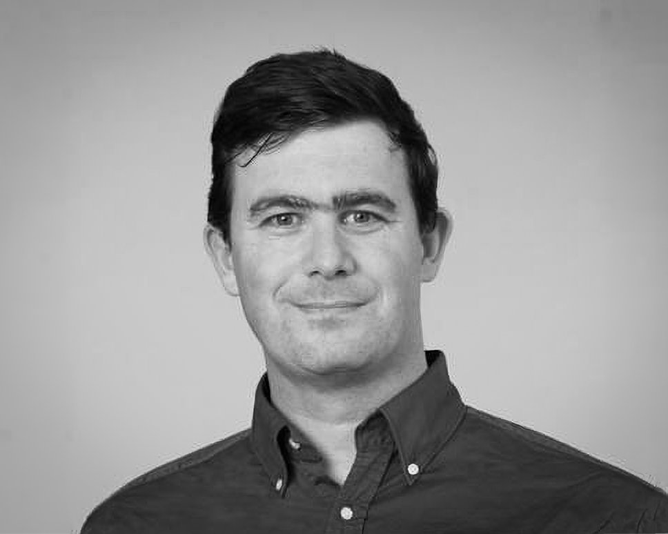 Black and white portrait of Chris Speed from Dunning Thornton Consultants. He has short, dark hair, and is wearing a buttoned-up shirt, smiling slightly, against a neutral background.