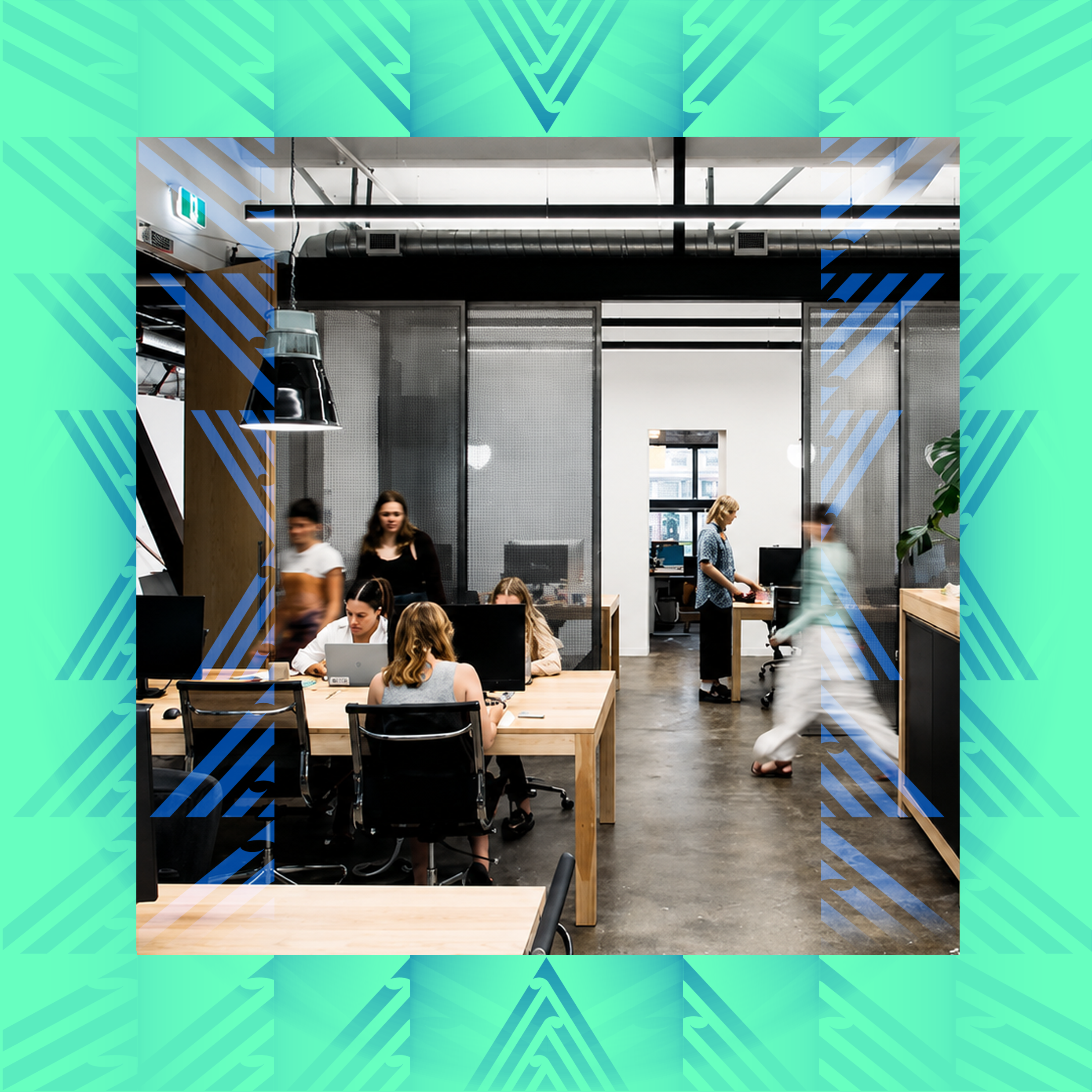 A view of the co-work space in The Exchange in Te Aro Courtenay. It shows modern office with people working at desks, large windows, and industrial ceiling pipes.