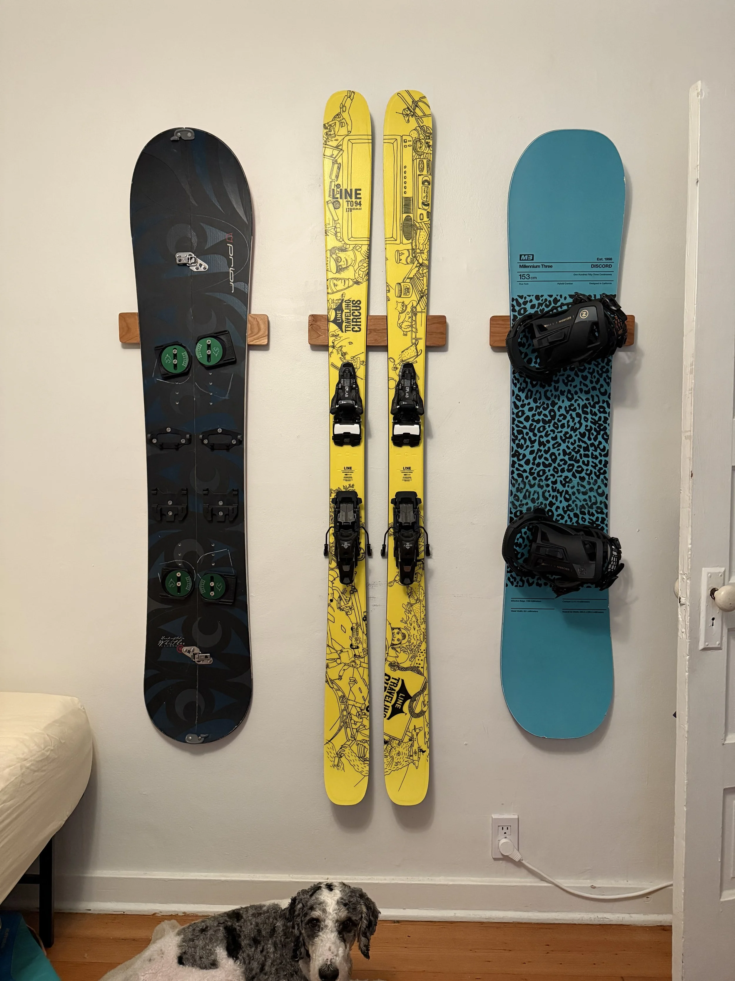 One pair of skis flanked by two snowboards, all mounted on Method Mounts™ on a white wall. The aesthetic is balanced left to right and up and down thanks to the adjustability afforded by the Method Mounts™.