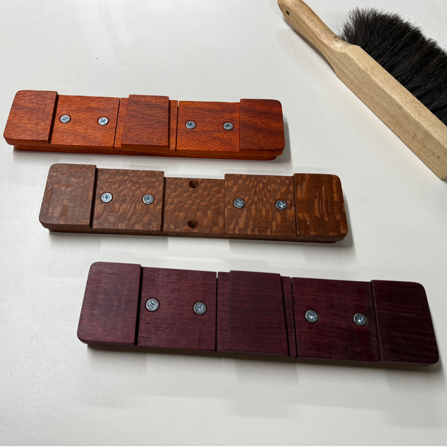 Three bespoke Method Mounts™ of various exotic wood species arranged in a row. The wood species are red alder, leopardwood, and purple heart.