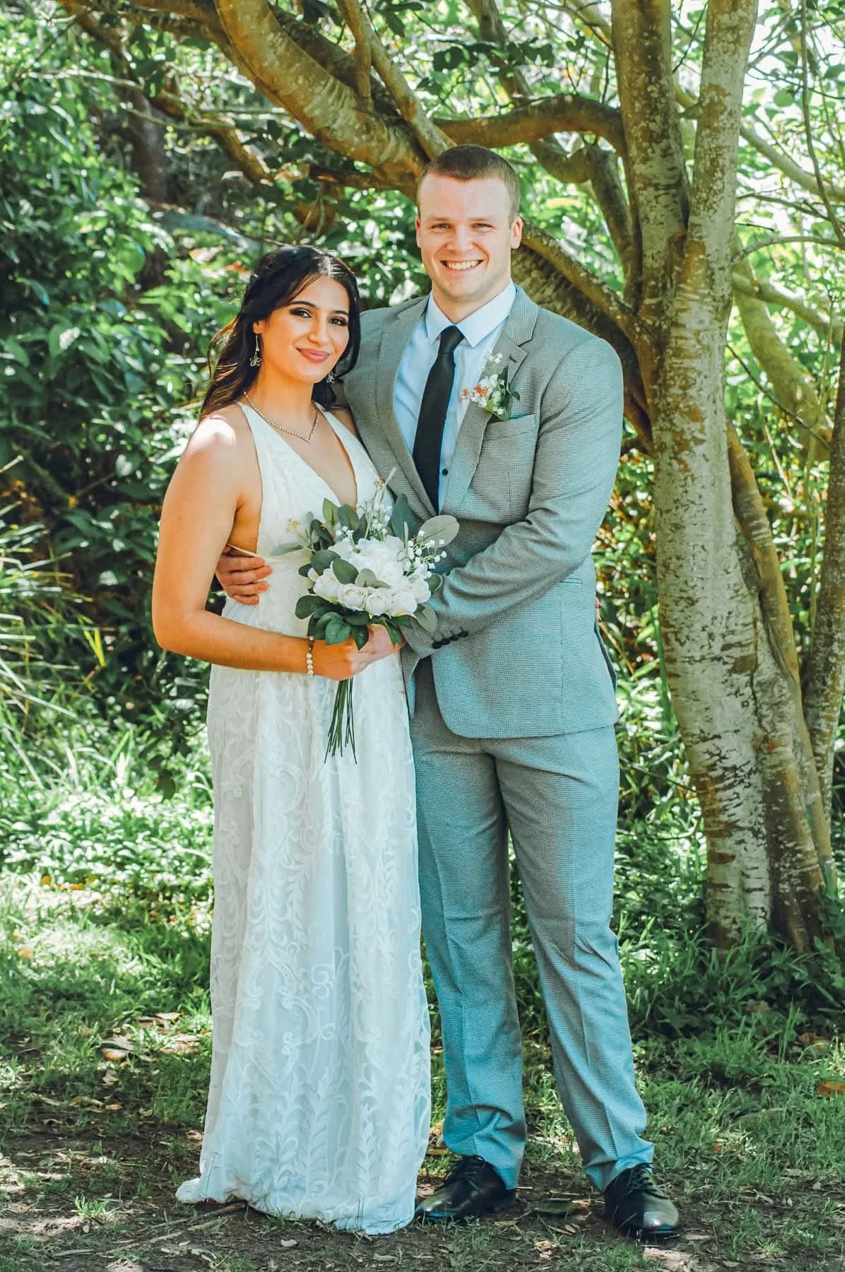 Portrait of newly wed couple posing under a tree.