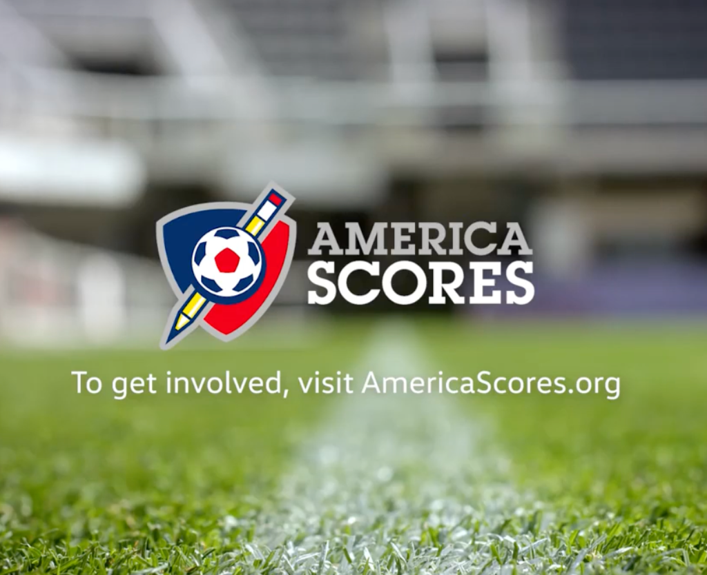 Logo of America Scores on a blurred background of a soccer field, with text inviting viewers to visit AmericaScores.org to get involved.