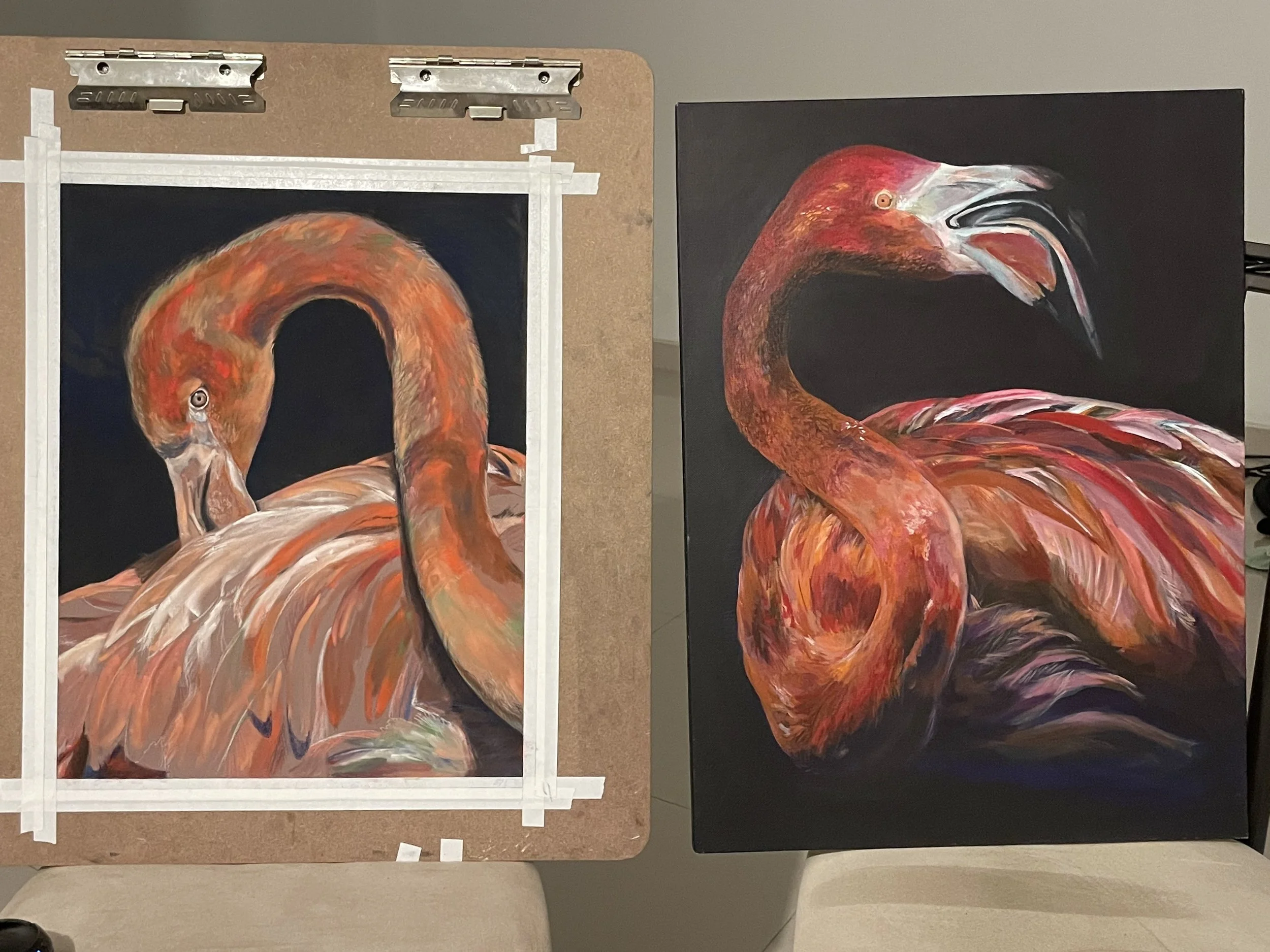 Two paintings of flamingos, one in progress on a brown drawing board and the other completed on a black canvas, both featuring vibrant red and orange colors.
