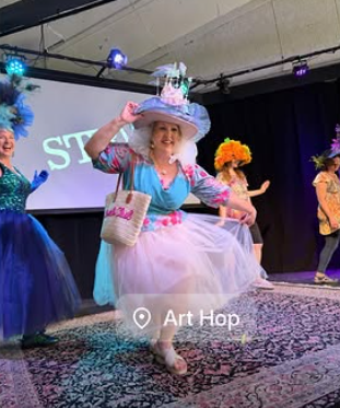 Group of women dressed in colorful, whimsical costumes performing on stage during a theatrical show.