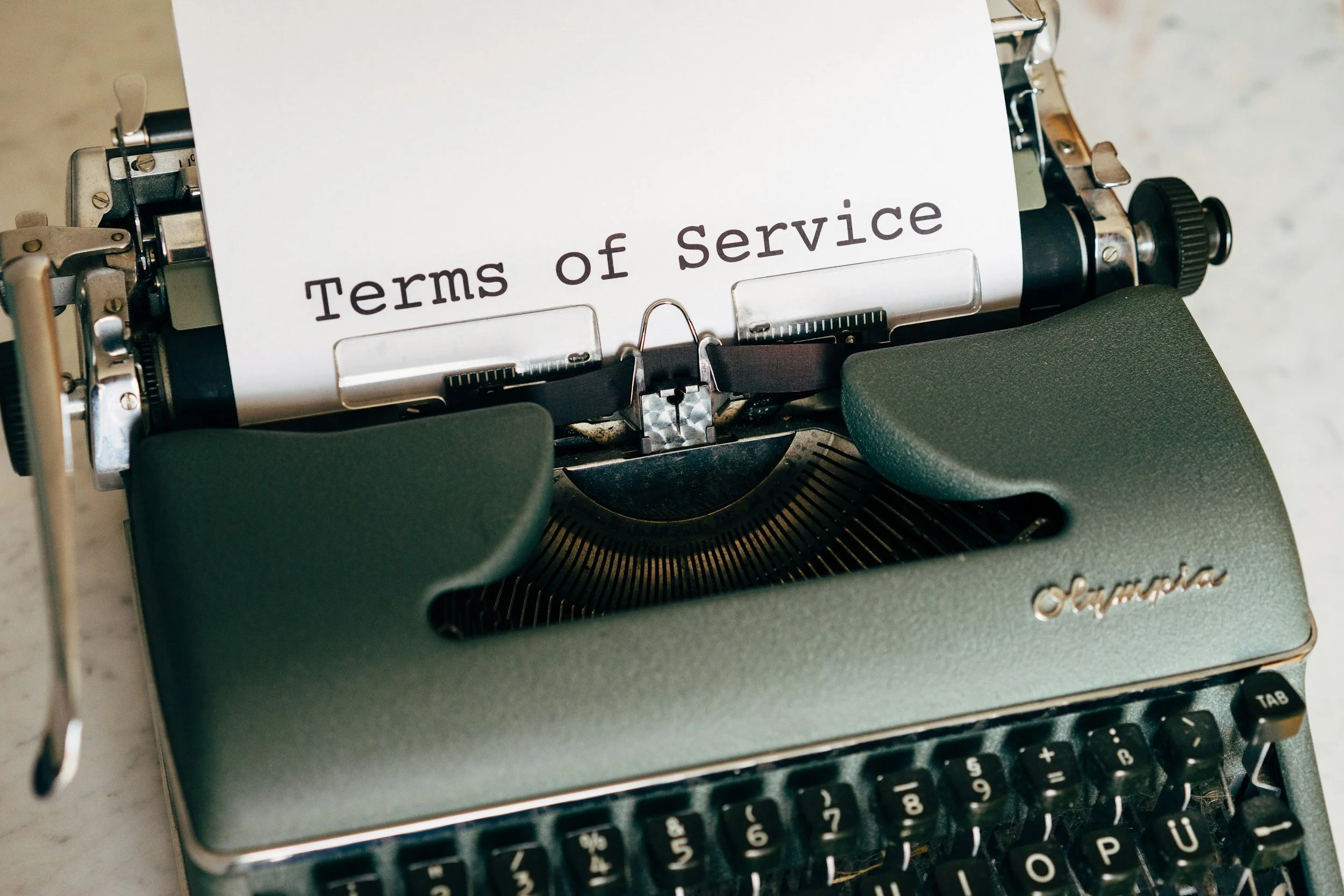 Typewriter with a paper that says 'Terms of Service' in black font.