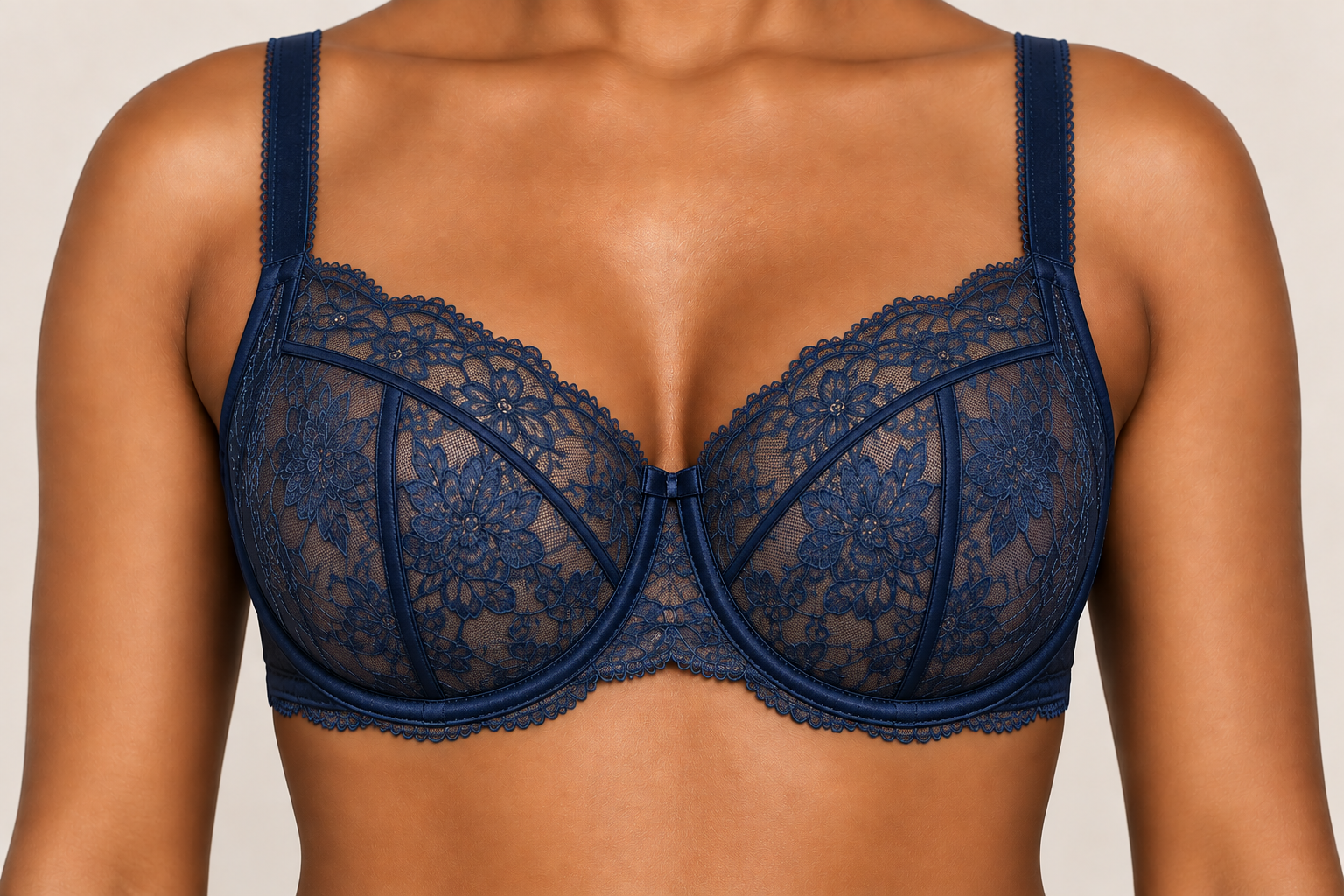 Close-up of a woman wearing a navy blue lace bra with floral patterns, featuring underwire support and satin straps.