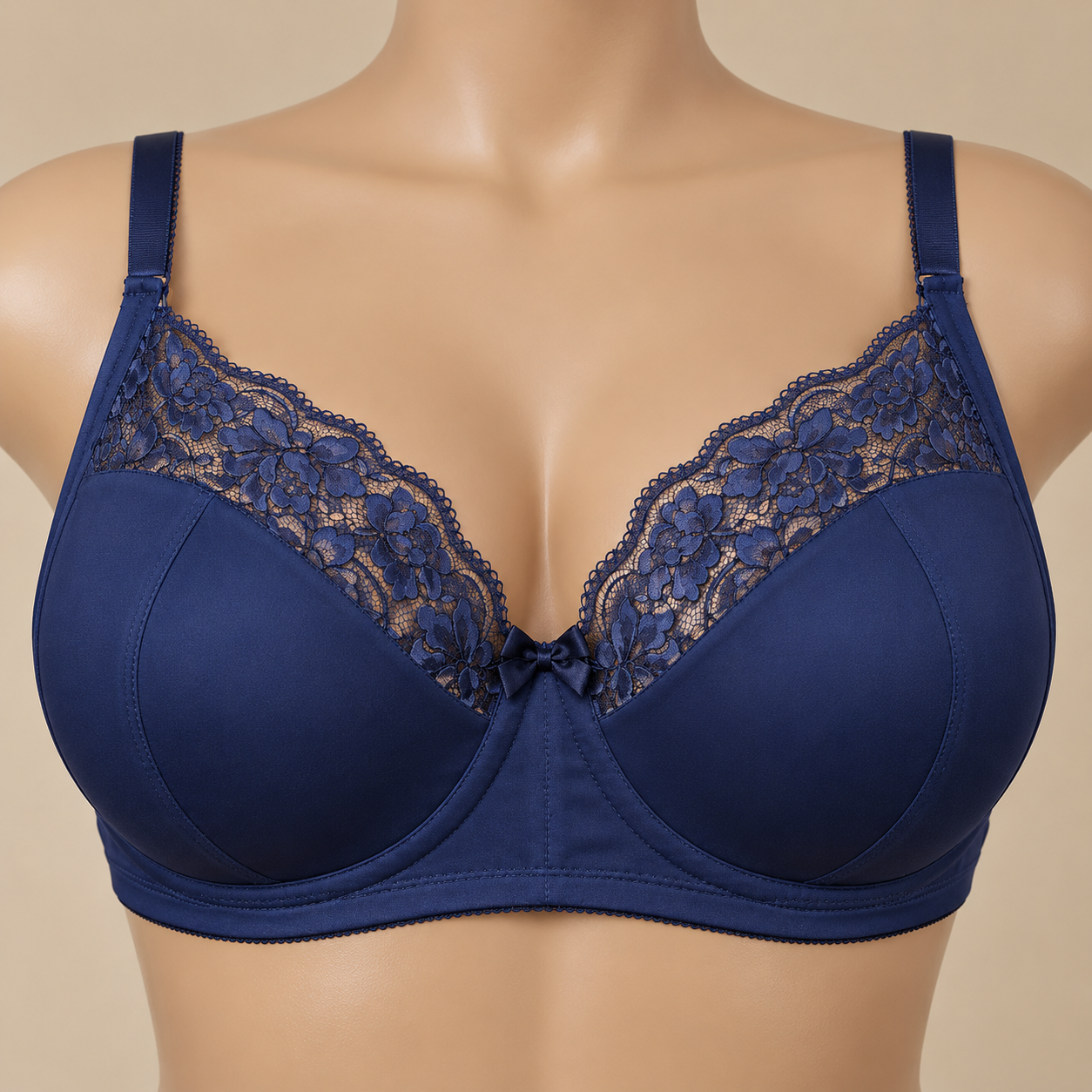 A mannequin wearing a navy blue bra with floral lace detail and a small bow in the center.